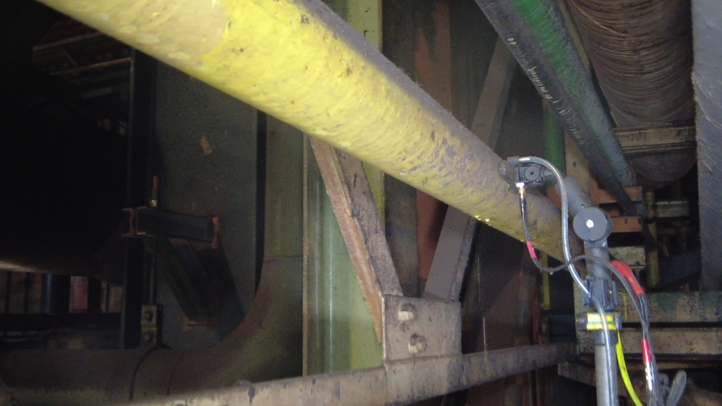 Close-up of industrial piping with sensors and electrical connections in a factory or plant setting.