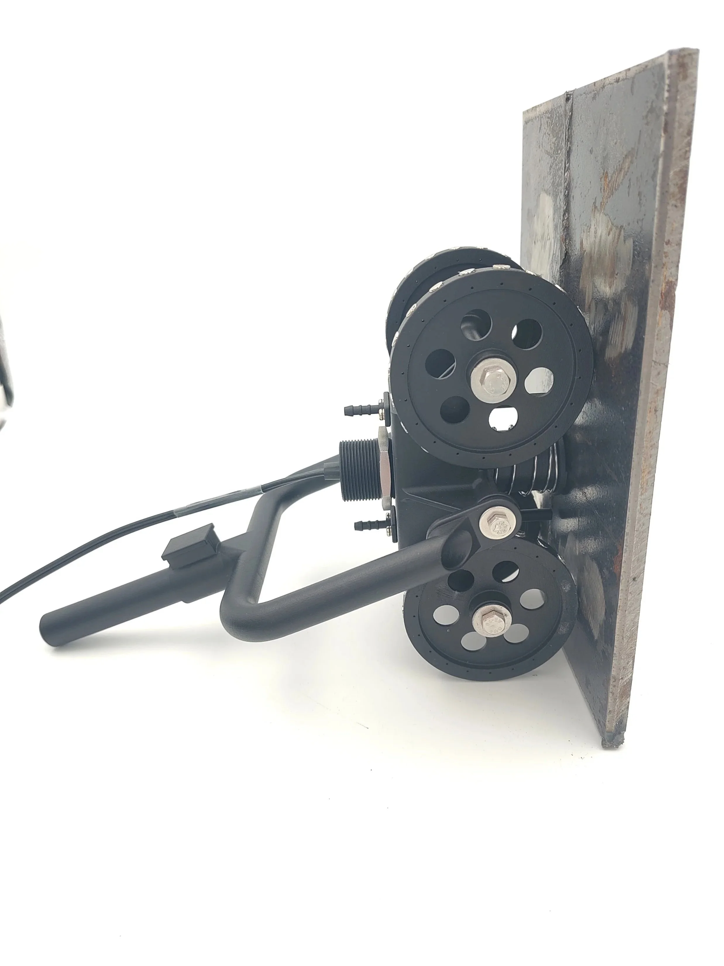 A black mechanical device with large circular wheels mounted on a metal base, with a bent handle and attached cables, against a plain white background.