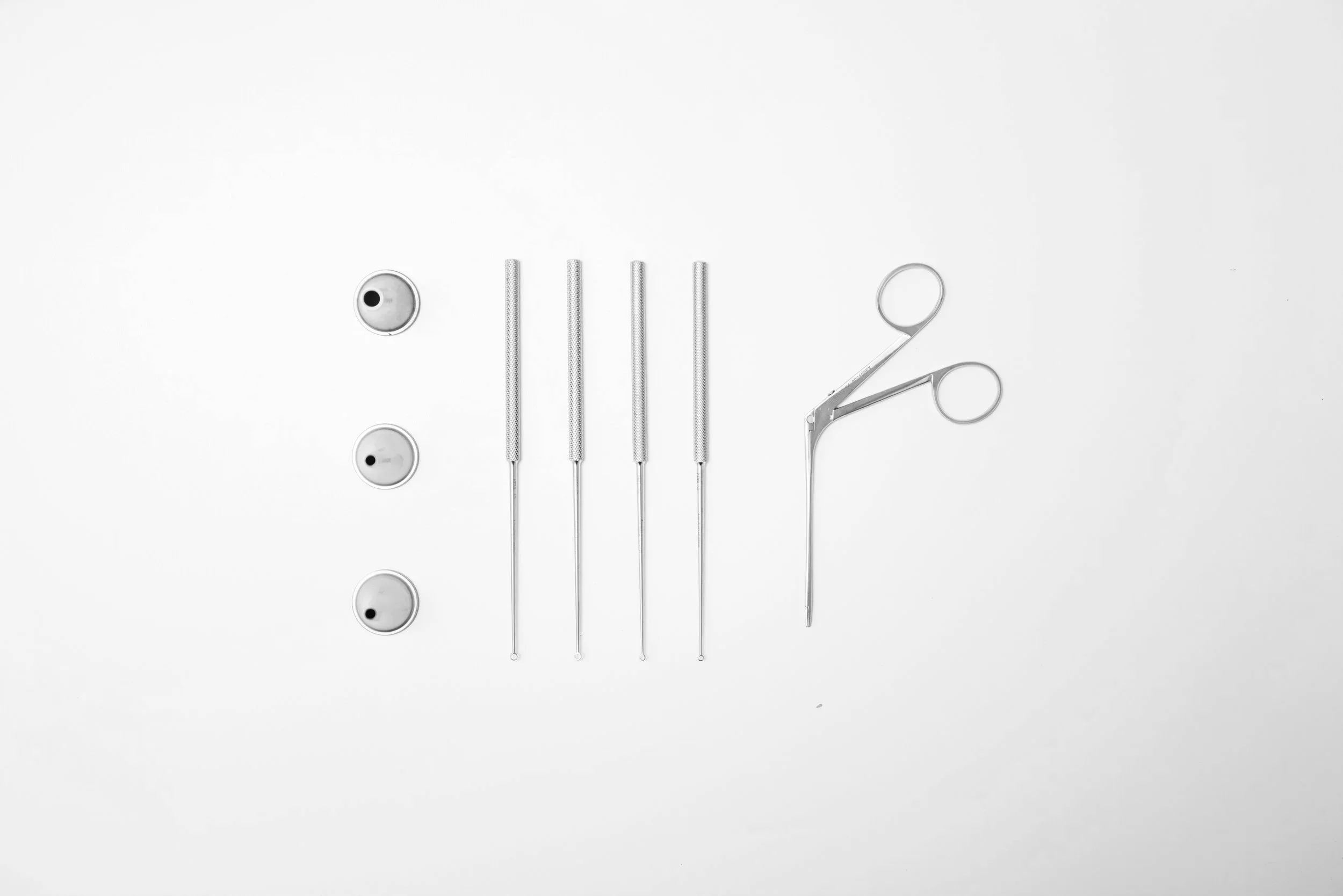 Surgical Instrumente, darunter Tupfer, Pinzetten und eine Skalpell, auf weißem Hintergrund.