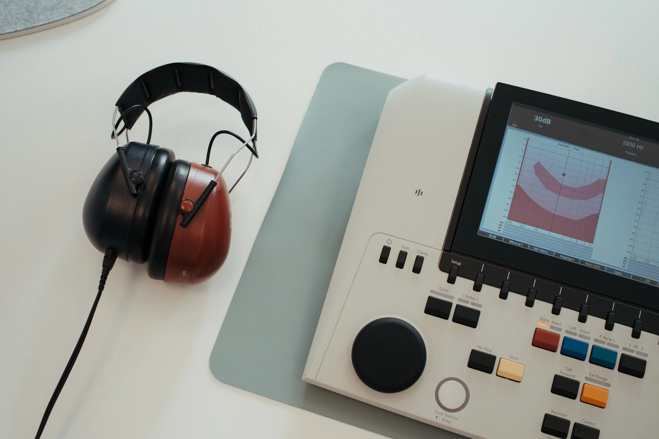 Audiogeräte, Kopfhörer und ein Bildschirm mit Audiowellenformen auf einem Tisch.
