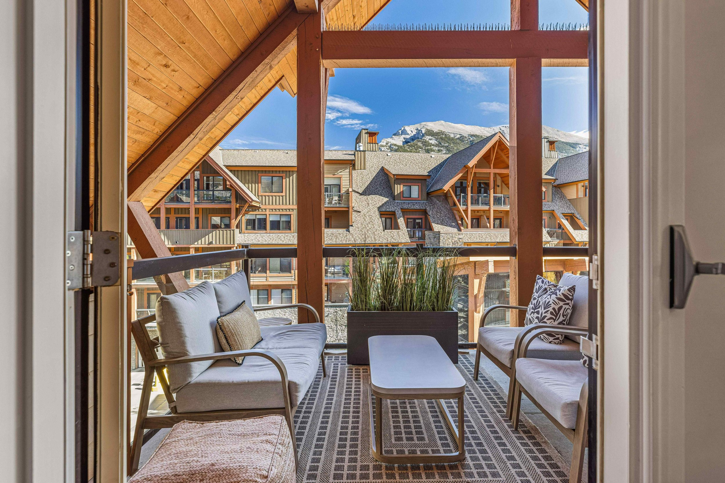 Balcony with outdoor furniture and a view of mountains and apartment buildings.