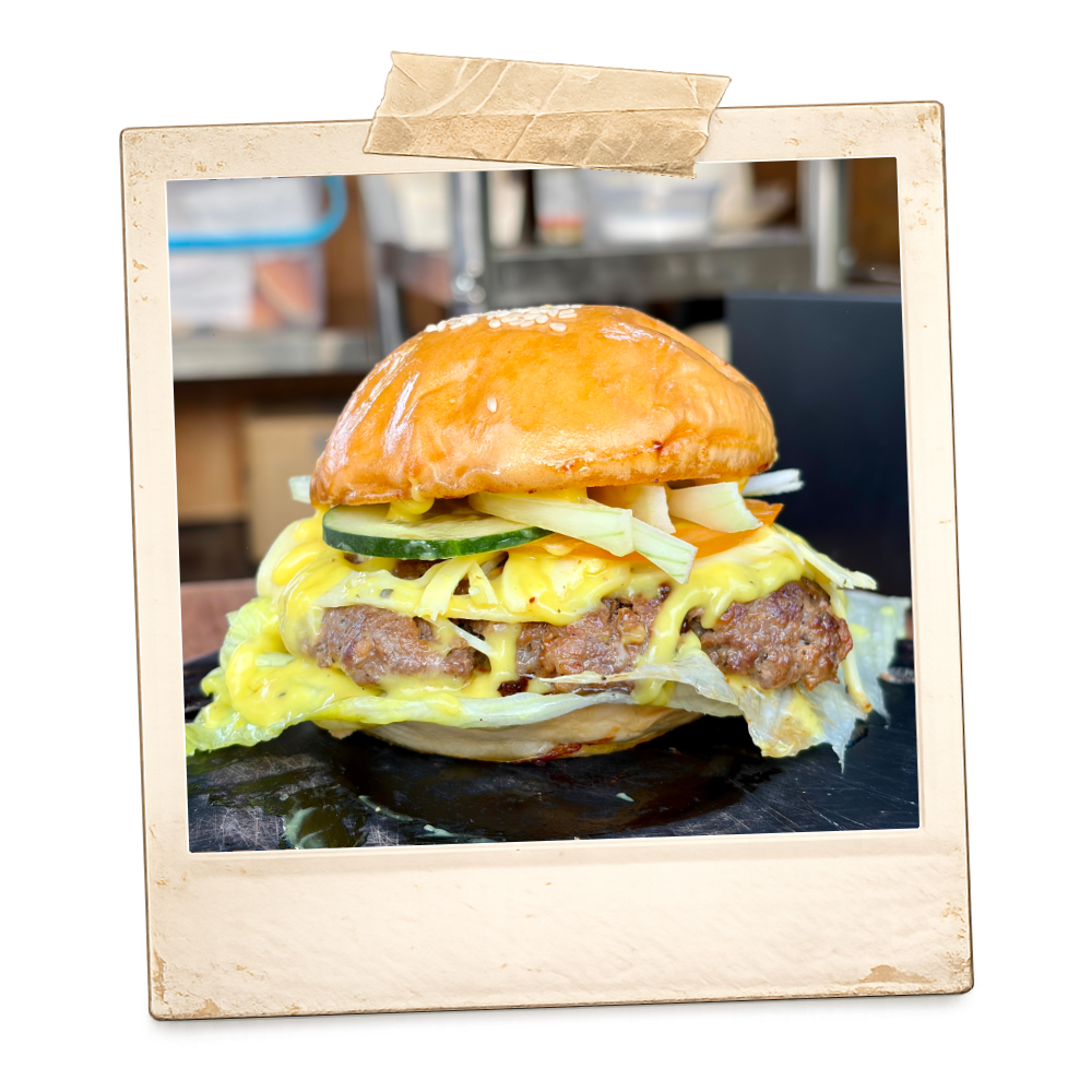 A cheeseburger with pickles, lettuce, cheese, and a beef patty in a bun.