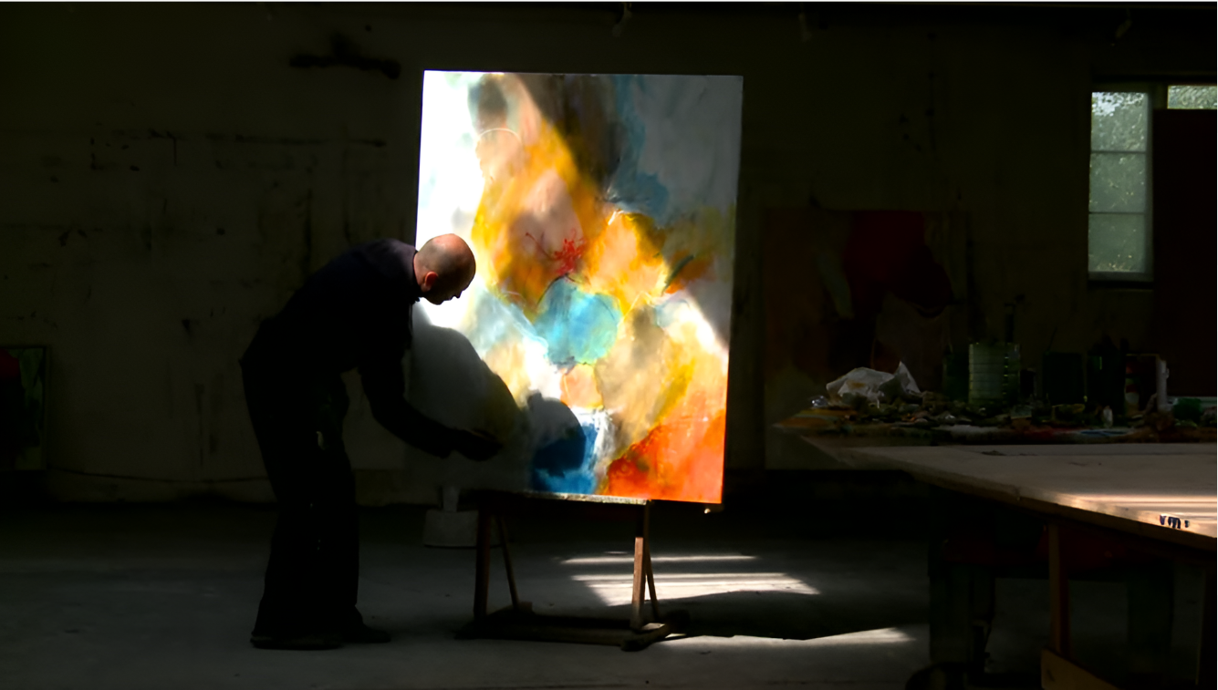 An artist working on a colorful abstract painting in a dimly lit studio with natural light coming through windows I Svend Kindt-Larsen I Abstract Artist I Copenhagen, Denmark