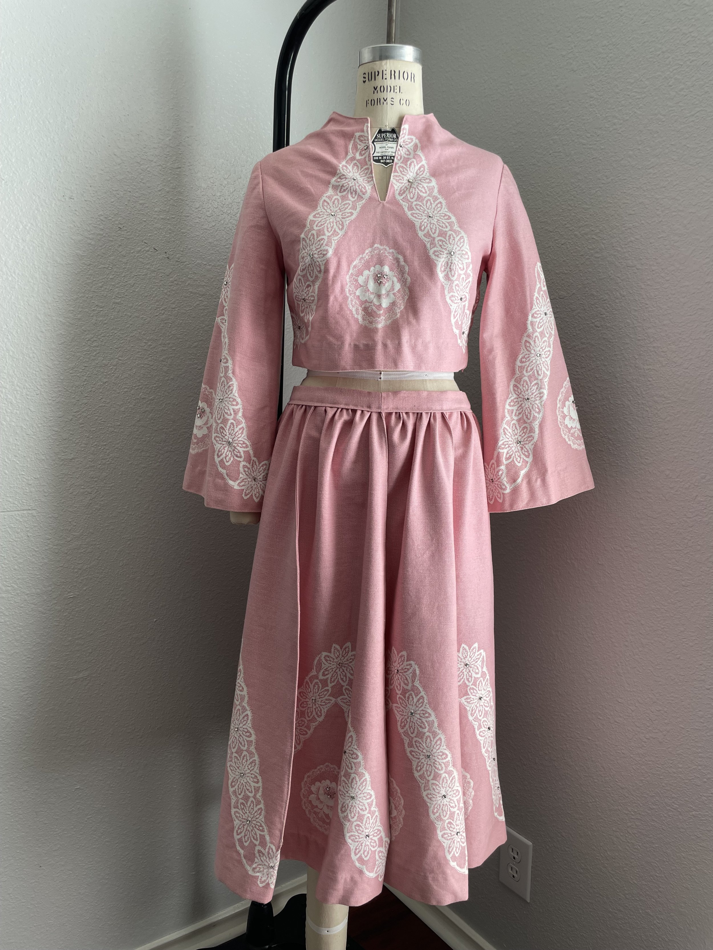 Pink vintage dress with white printed detail displayed on a mannequin.