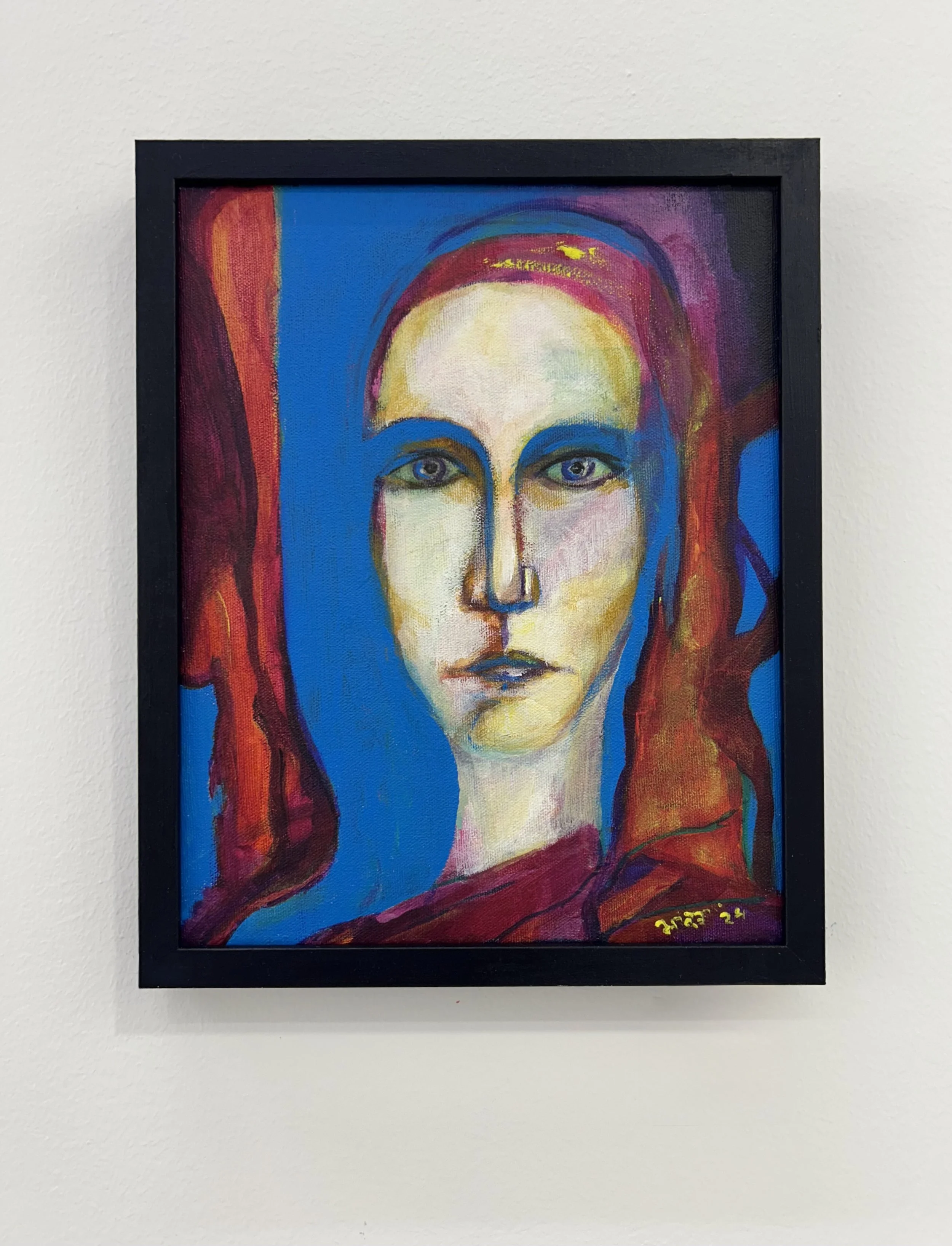 Close-up of an abstract painting of a woman's face with large, expressive eyes, colored with shades of blue, yellow, purple, and red, framed in black.