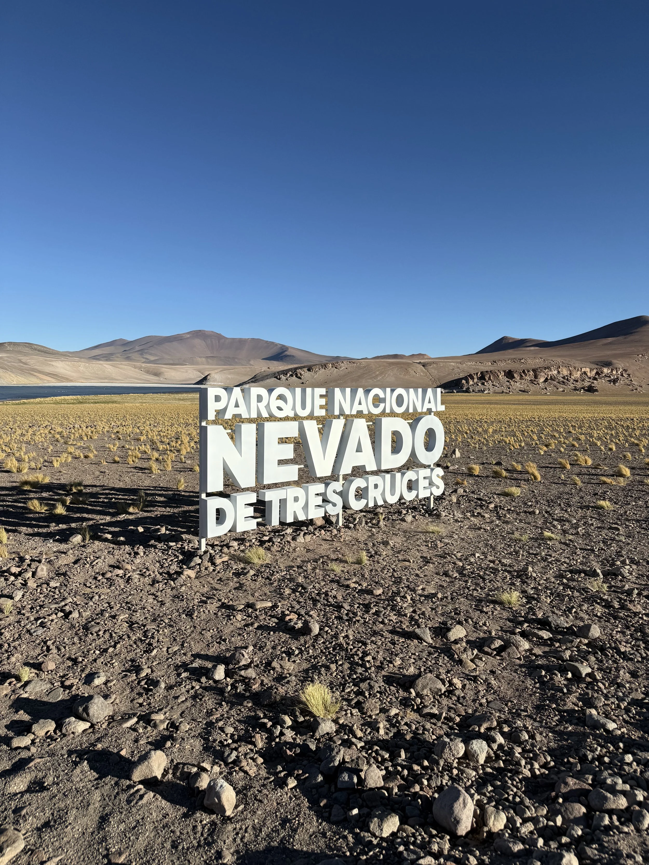 Sign in the desert at Parque Nacional Nevado de Tres Cruces with mountains in the background.