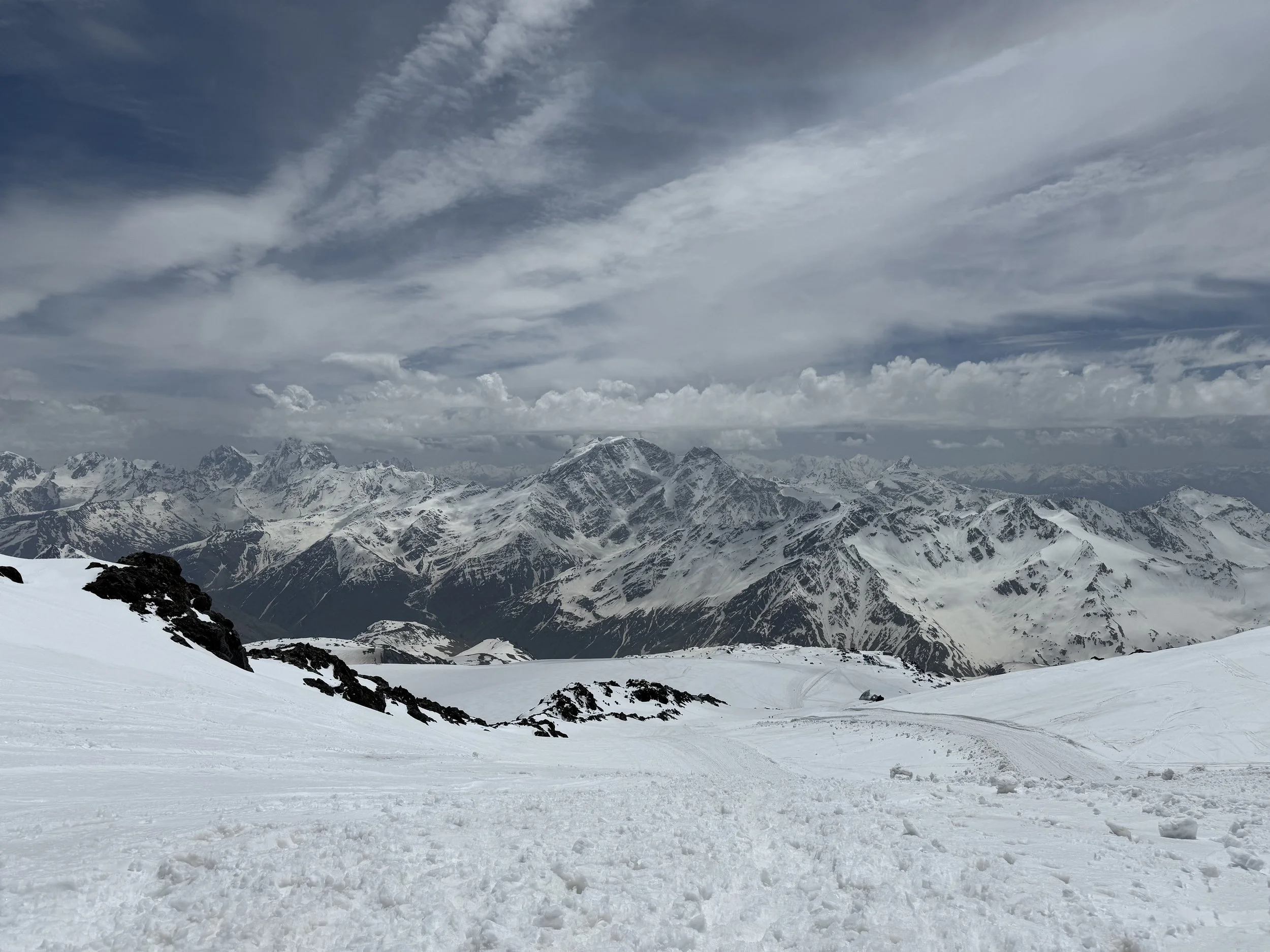 Snow-covered mountain landscape with rugged peaks under cloudy sky.