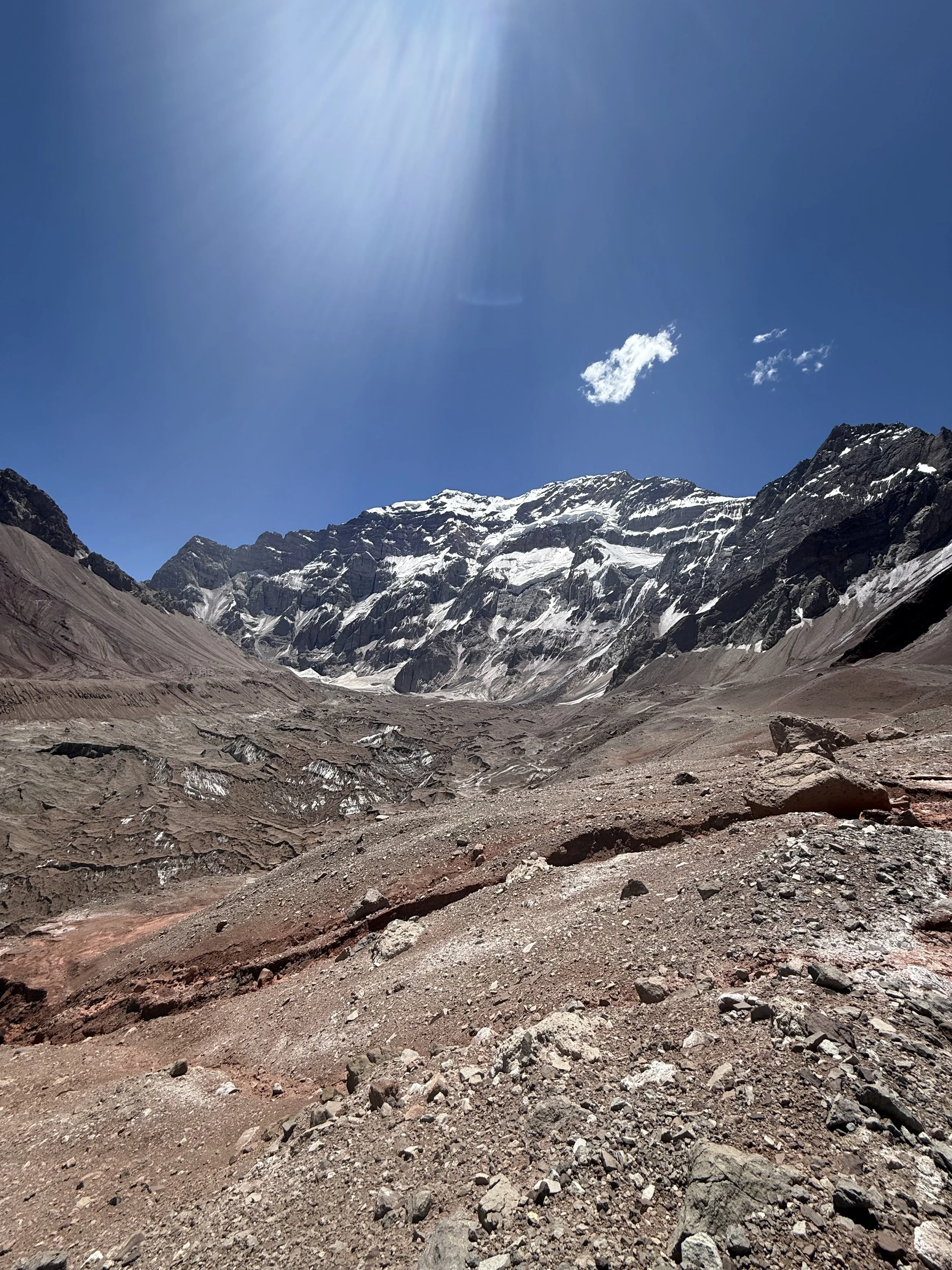 Mountain landscape with snow-capped peaks under a clear blue sky and bright sunlight.