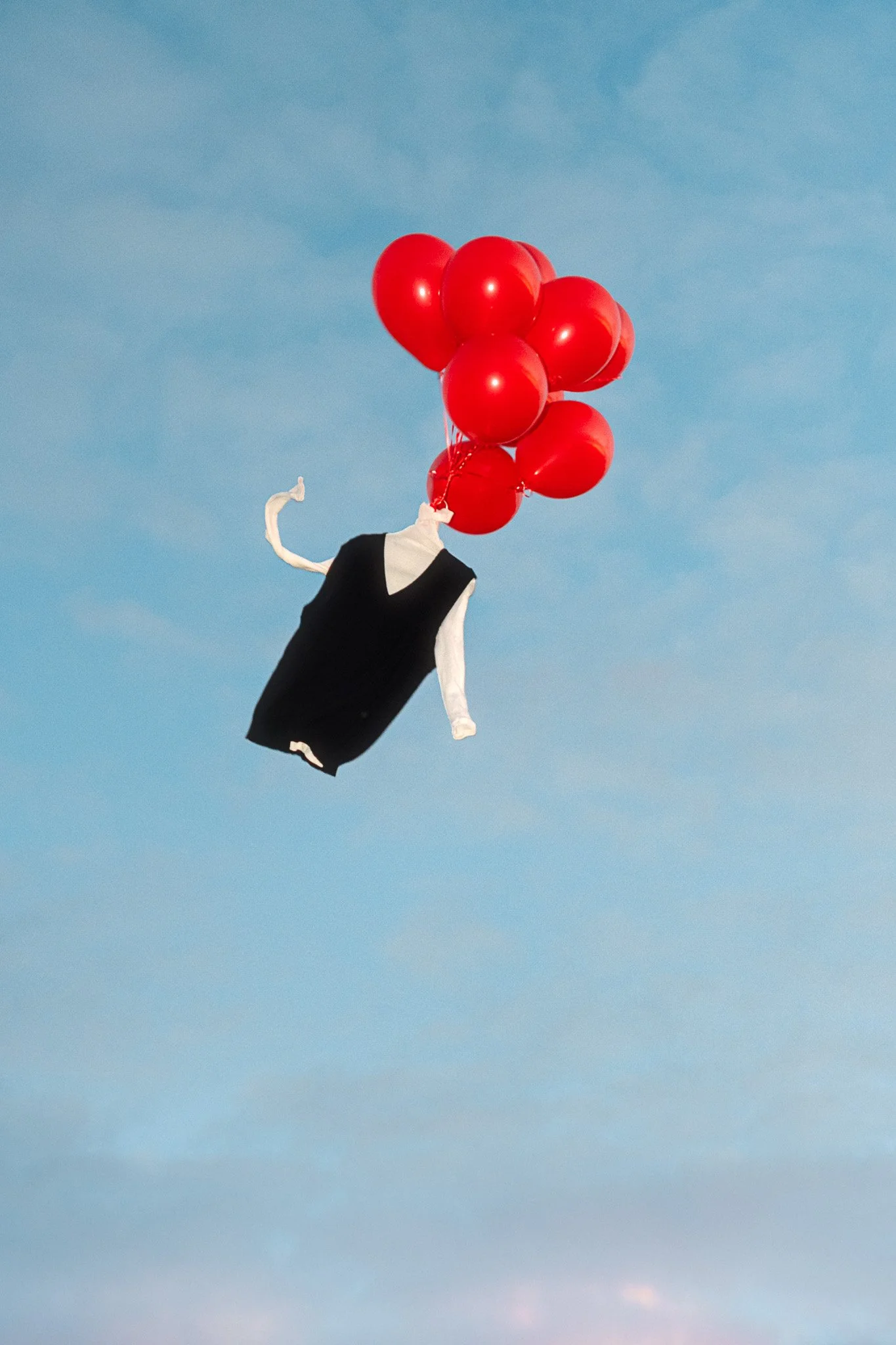 Arnsdorf fashion piece floating with red balloons – surreal editorial photography