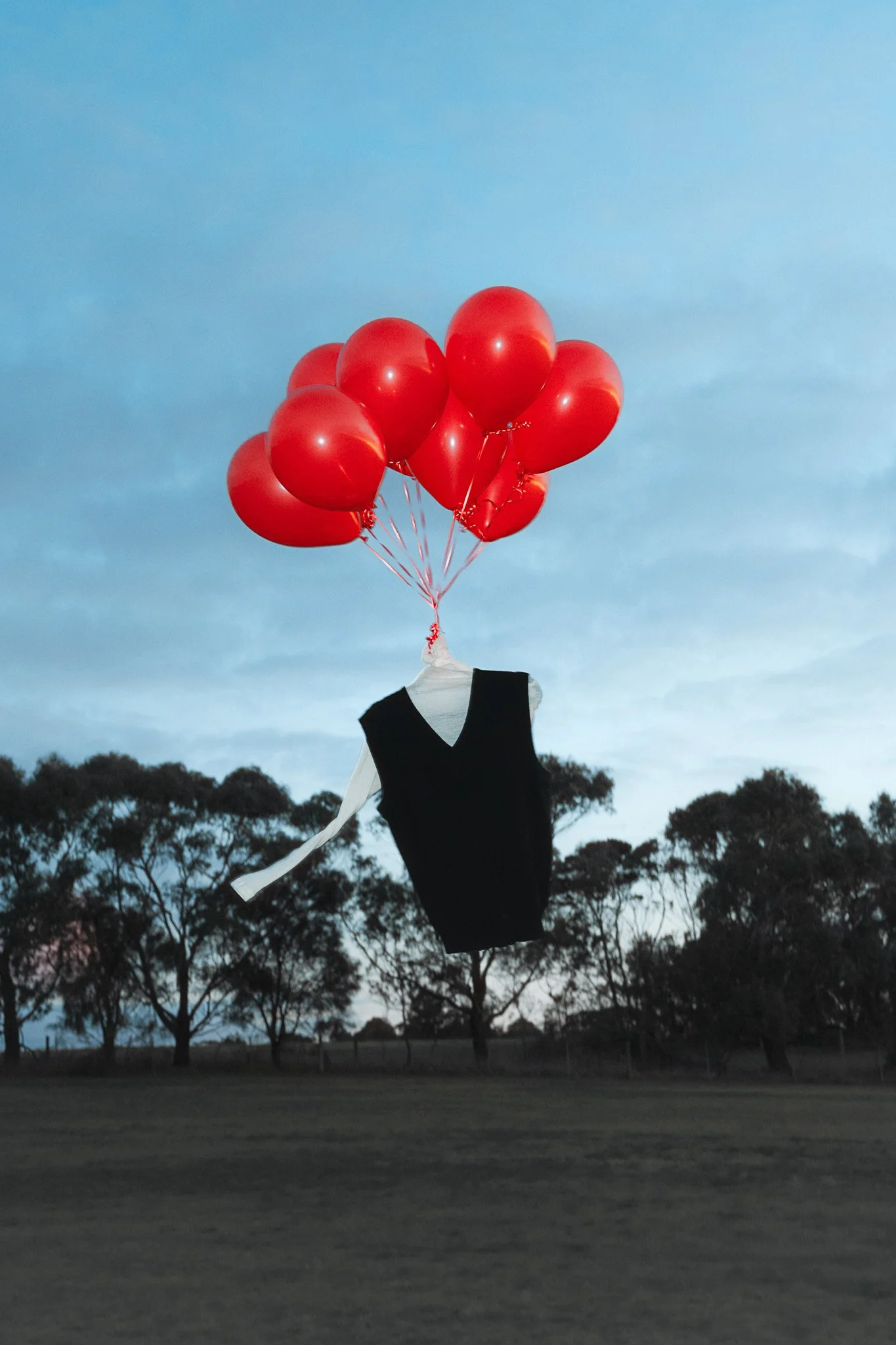 Arnsdorf fashion piece floating with red balloons – surreal editorial photography
