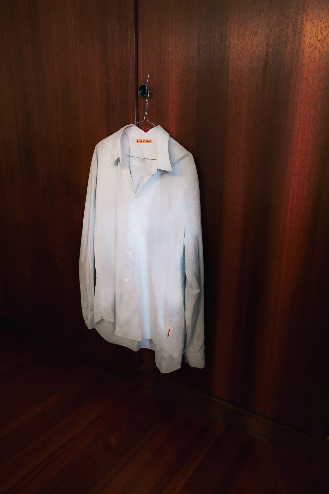 Acne Studio blue shirt hanging on timber doorknob