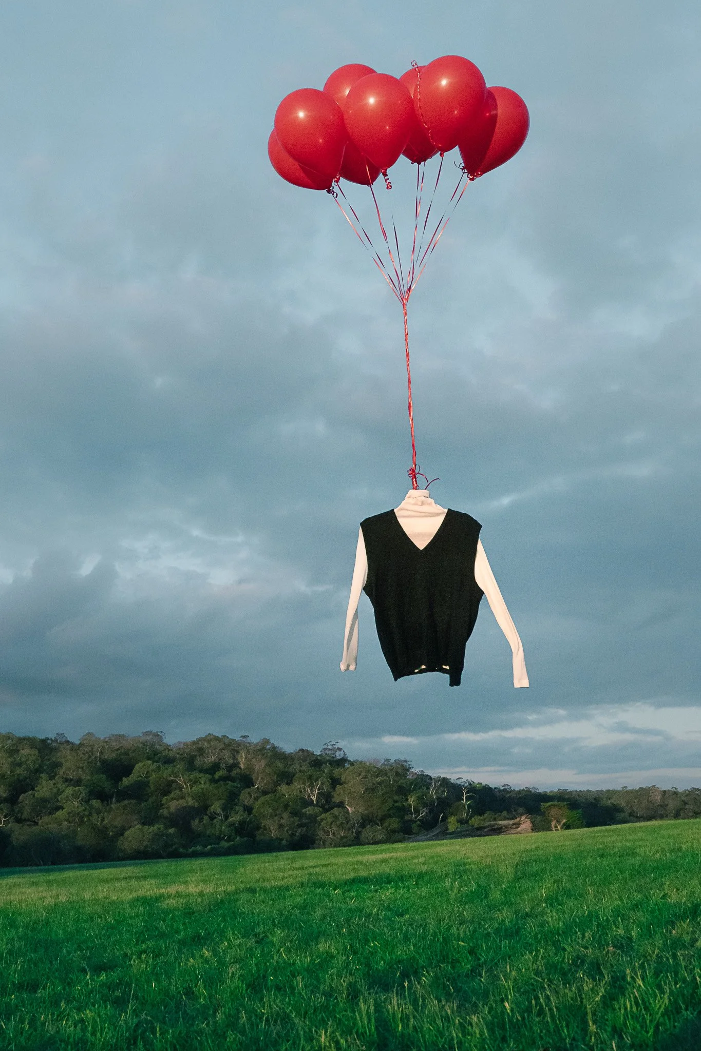 Arnsdorf fashion piece floating with red balloons – surreal moody editorial photography