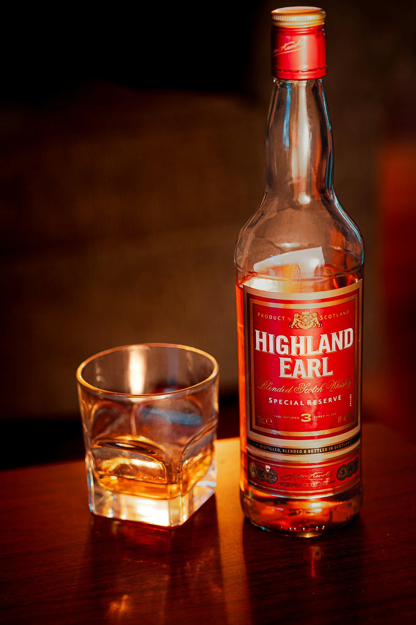 Glass of Highland Earl scotch on dining table with candlelight – moody lifestyle wine photography