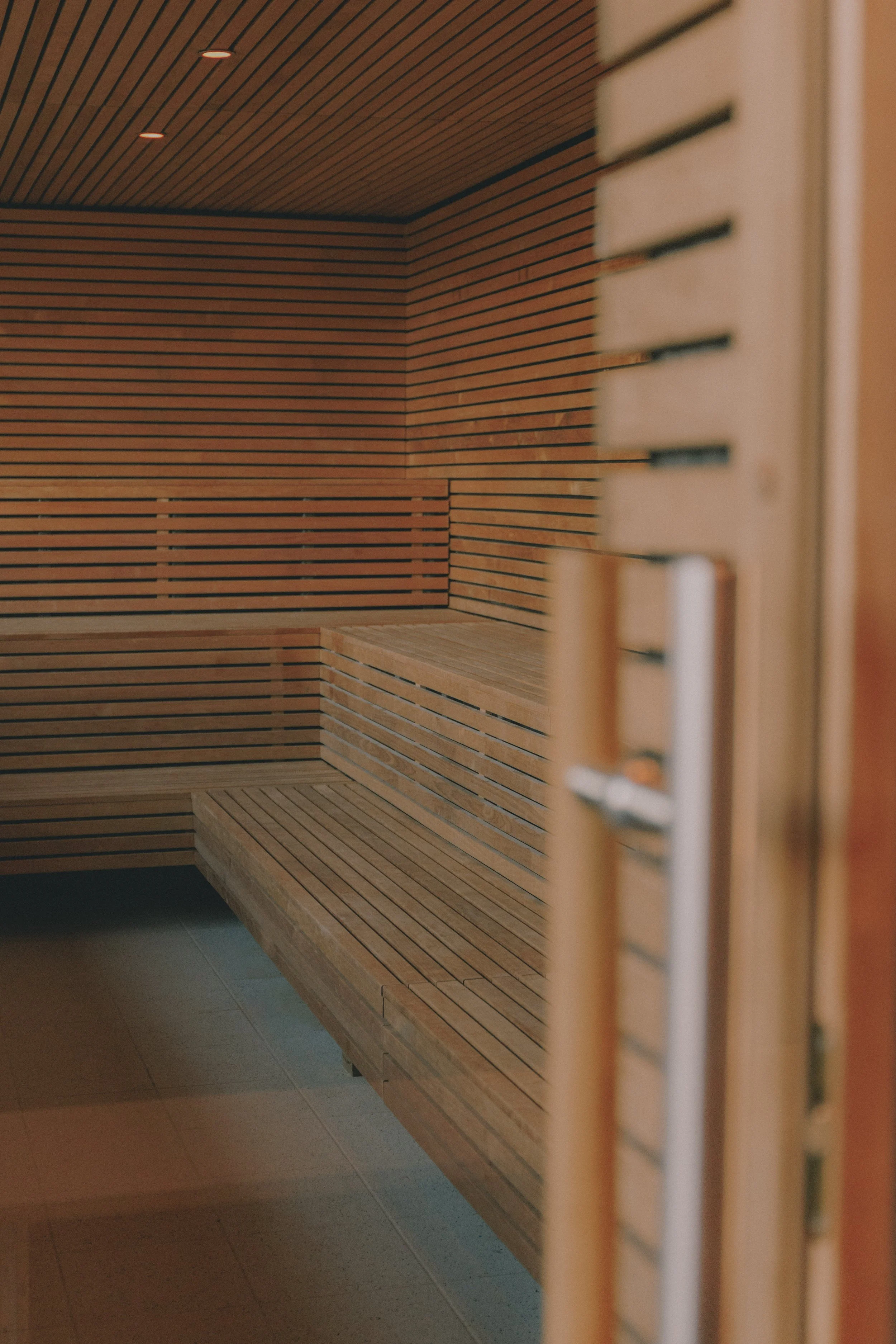 Interior of a wooden sauna room with benches and perforated walls. Holm8