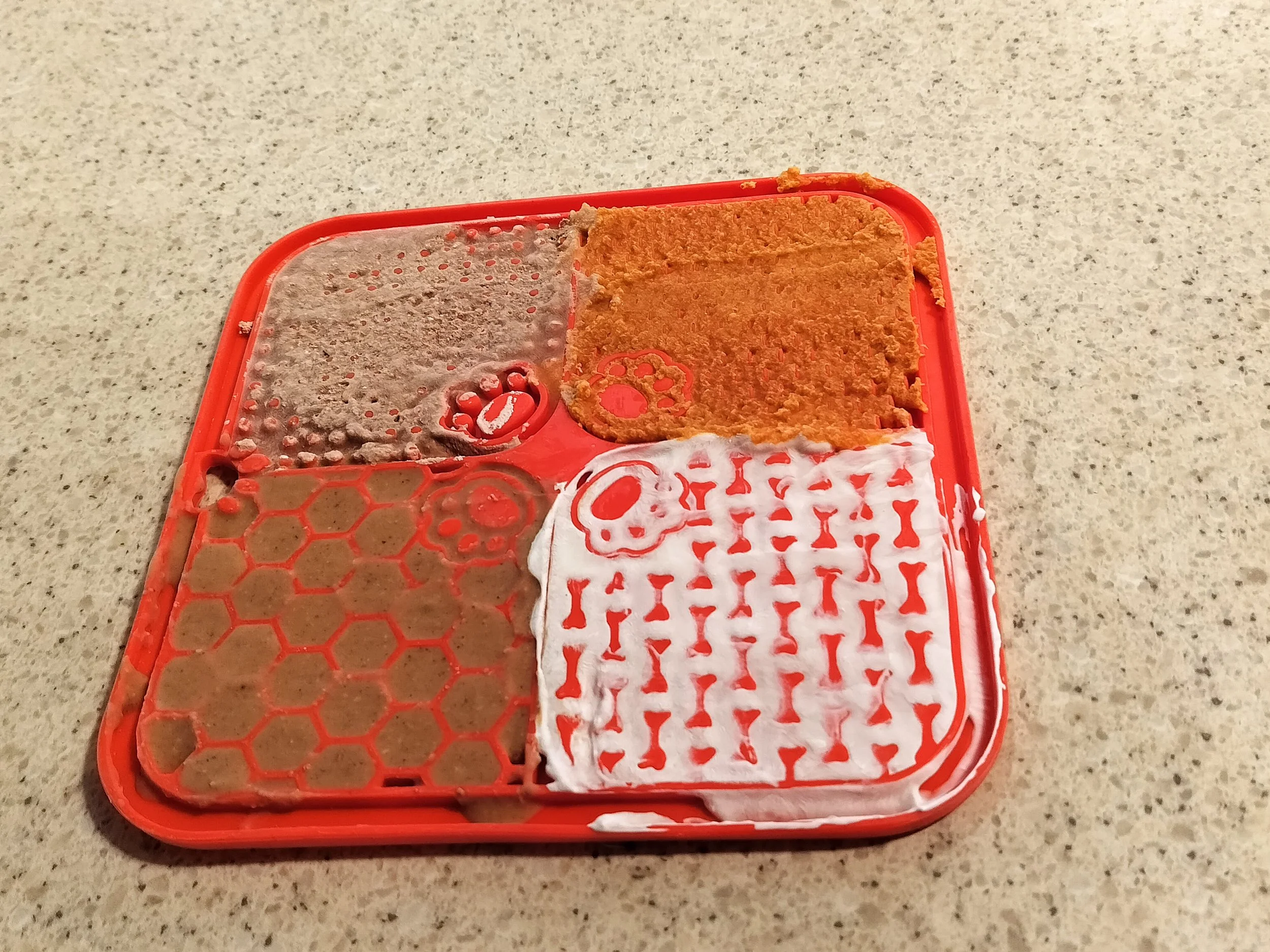A frozen silicone lick mat smeared with dog food, pumpkin puree, peanut butter, and plain yogurt
