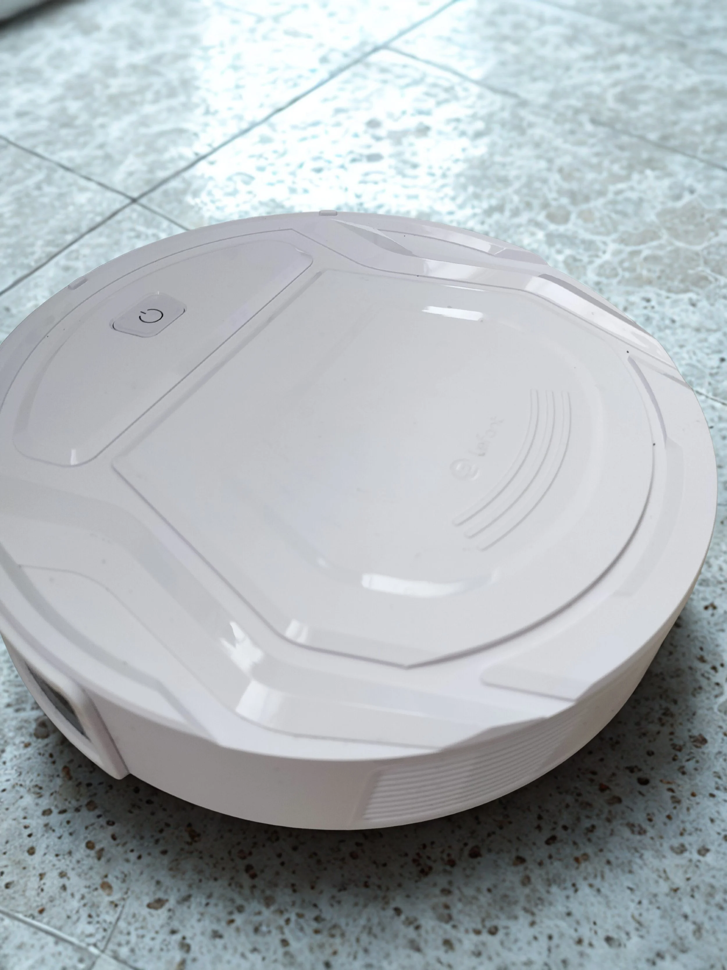 a white robot vacuum crossing a tile floor