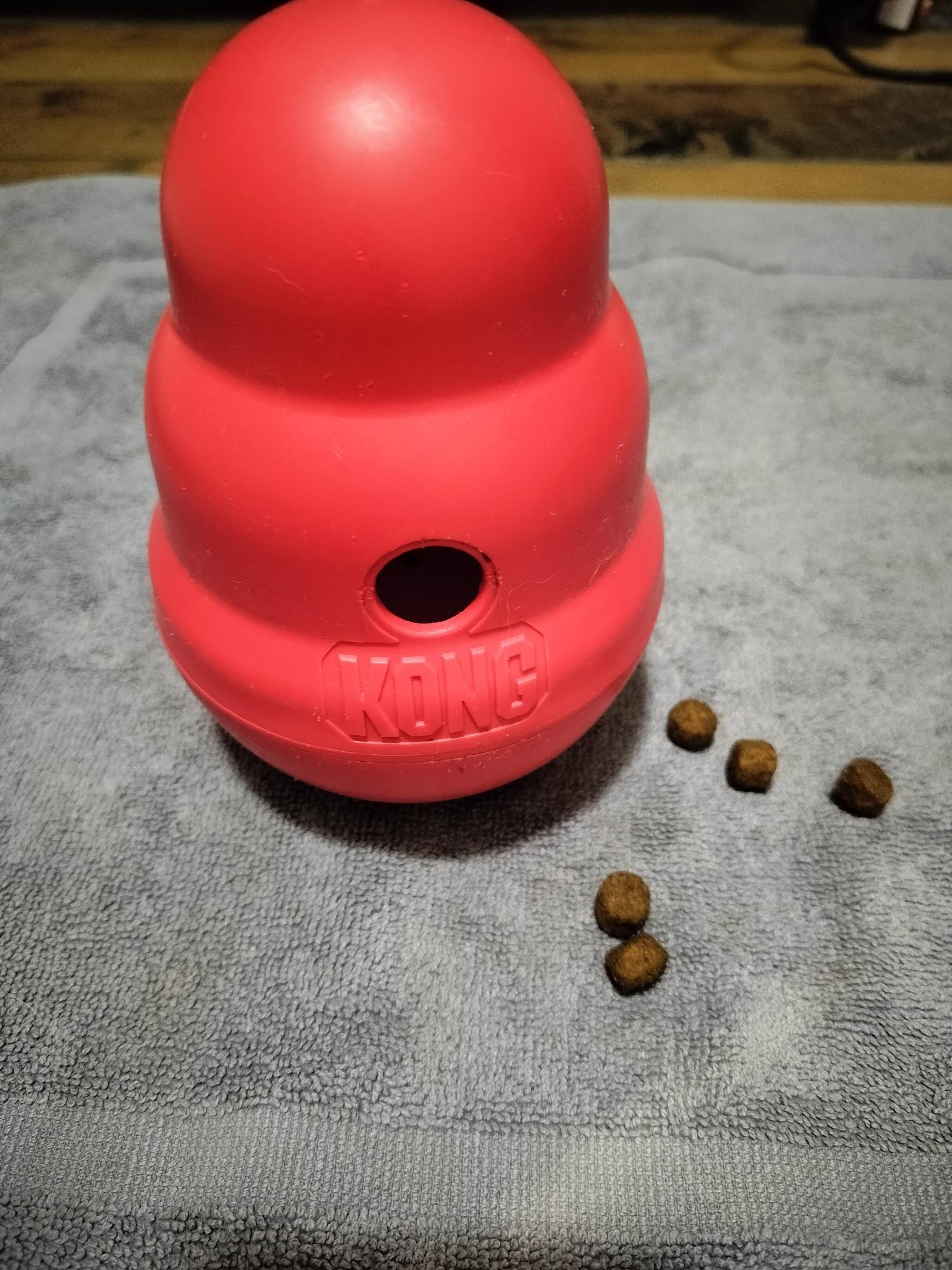 A red treat-dispensing tool with a few pieces of kibble falling out