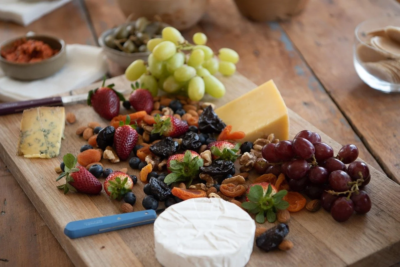 A platter covered with a variety of cheeses, grapes, and dried fruits