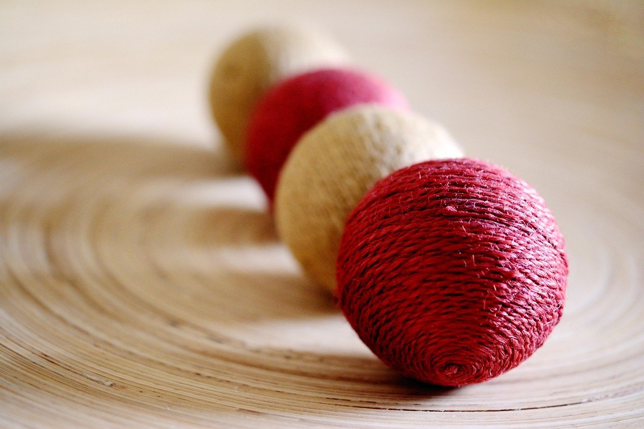 Four sisal covered balls lined up on a bamboo plate,. Natural products are best for a healthy cat and a healthy planet.