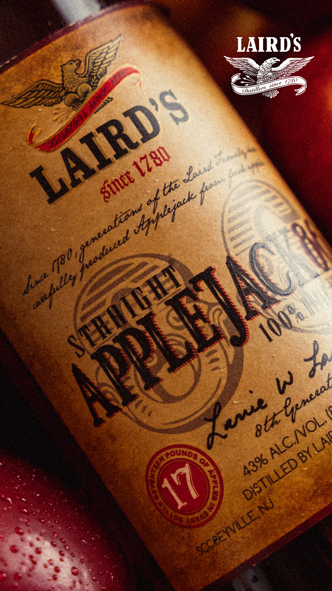 Close-up of a Laird's Applejack label featuring a vintage-style eagle logo, red and black text, and info about the product's history and alcohol content.