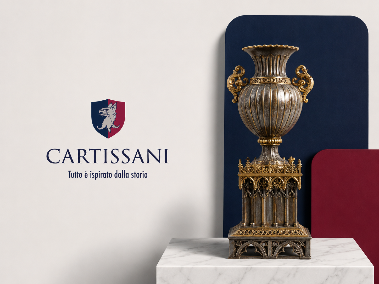 A vintage urn with gold accents placed on a decorative stand, against a backdrop with navy and red panels, on a white marble surface, next to a wall with a logo of a wolf’s head crest and the text "CARTISSANI" and "Tutto è ispirato dalla storia".