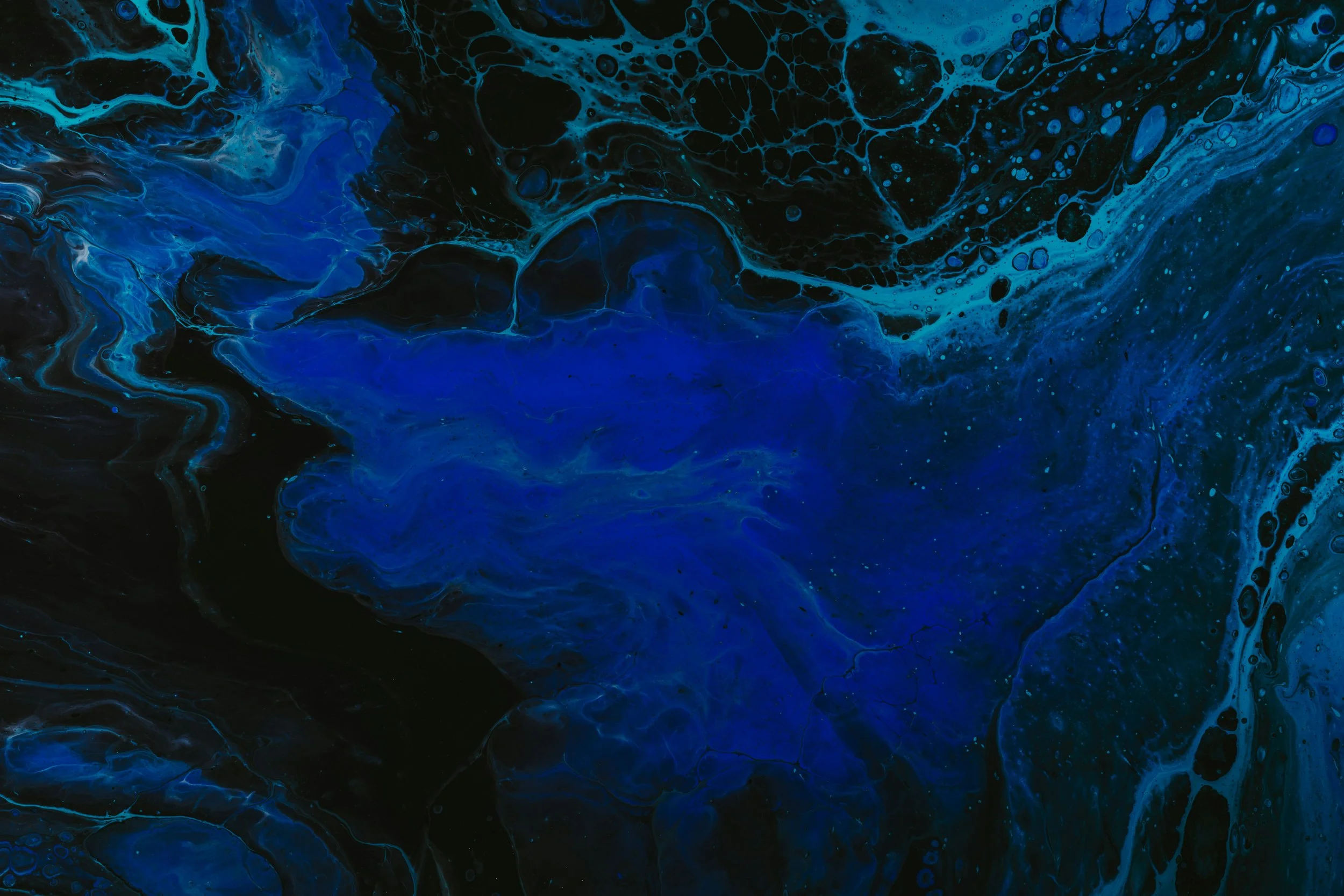 Abstract blue and black swirling liquid or paint with bubbles and cellular patterns.