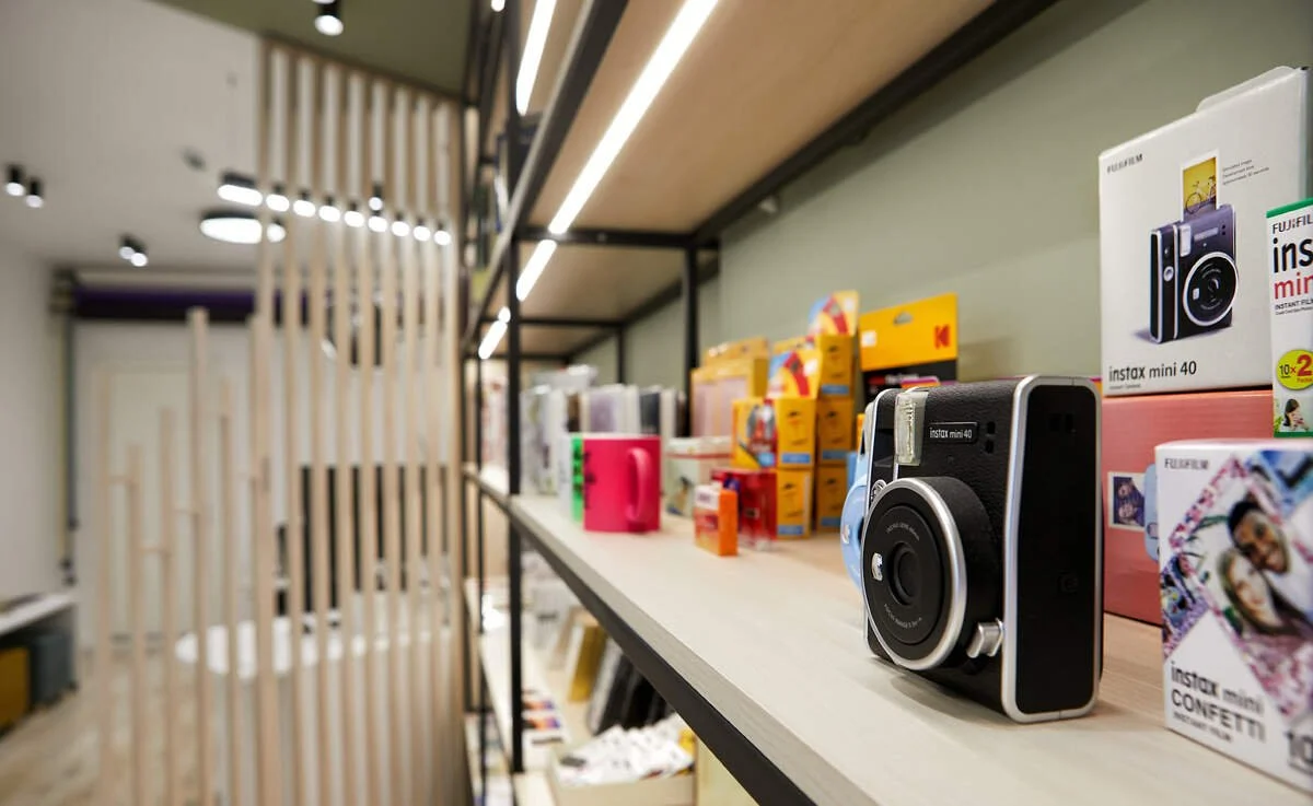 Shelf displaying Fujifilm instant cameras and photo boxes in a retail store.