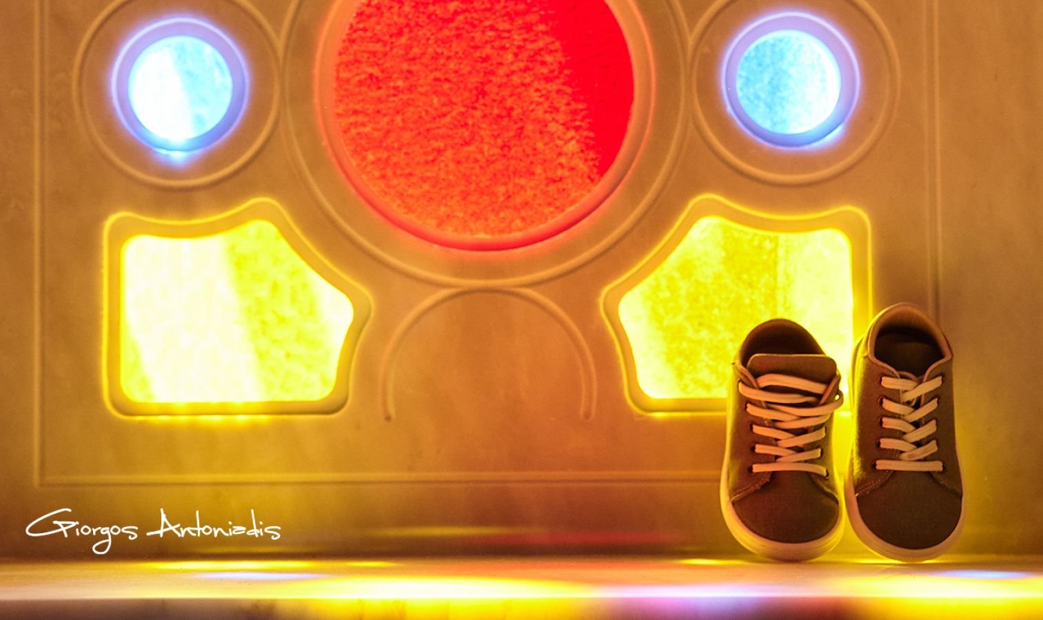 Shoes next to illuminated game or arcade machine with colorful lights of red, yellow, and blue.