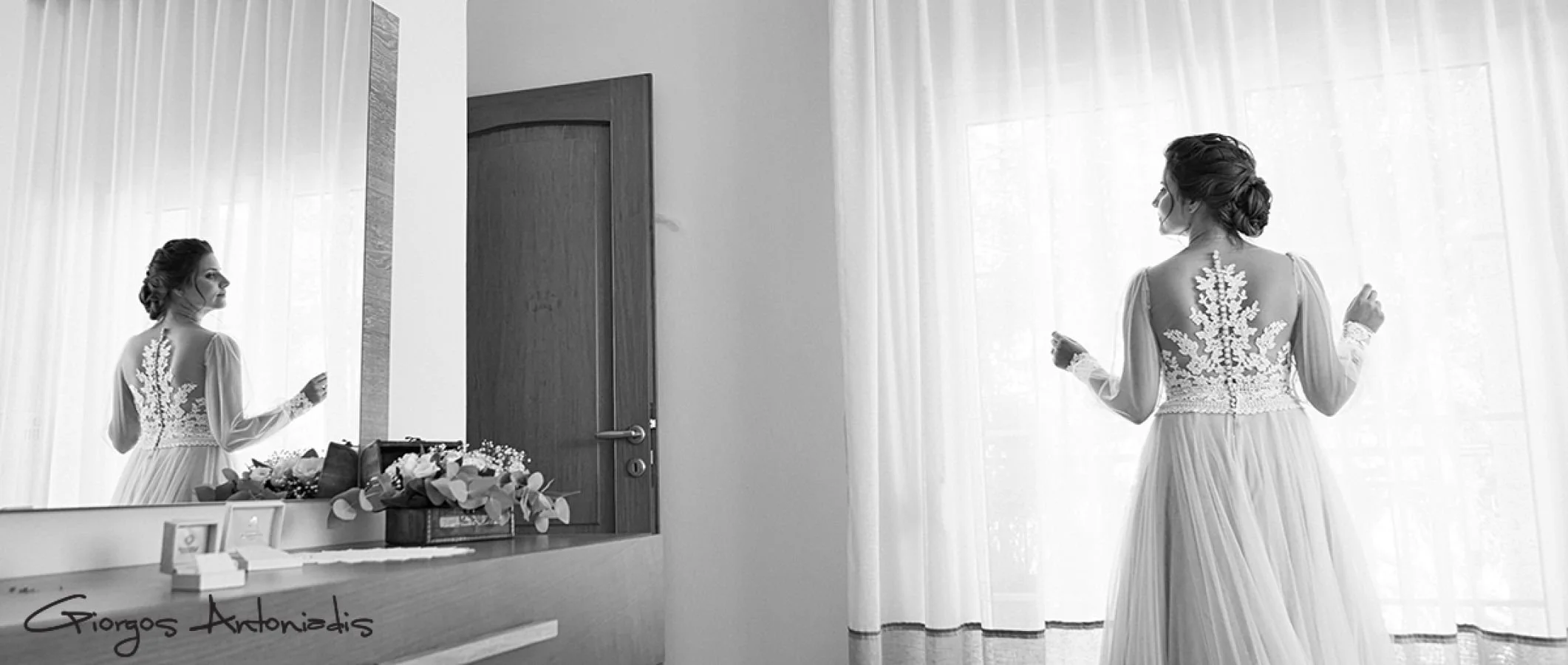 A woman in a bridal gown looking at herself in a mirror beside a wooden door, with curtains and a window in the background.