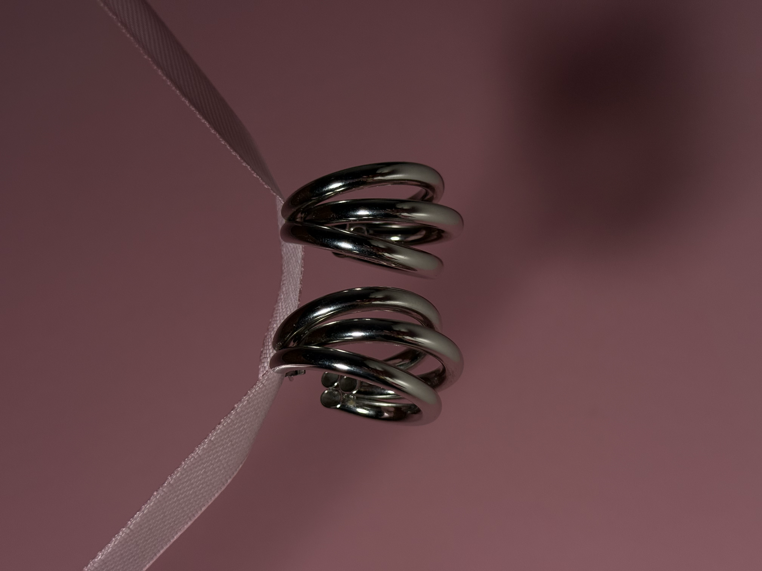 Twee metalen spiraalverpakkingen met een roze lint op een roze achtergrond.