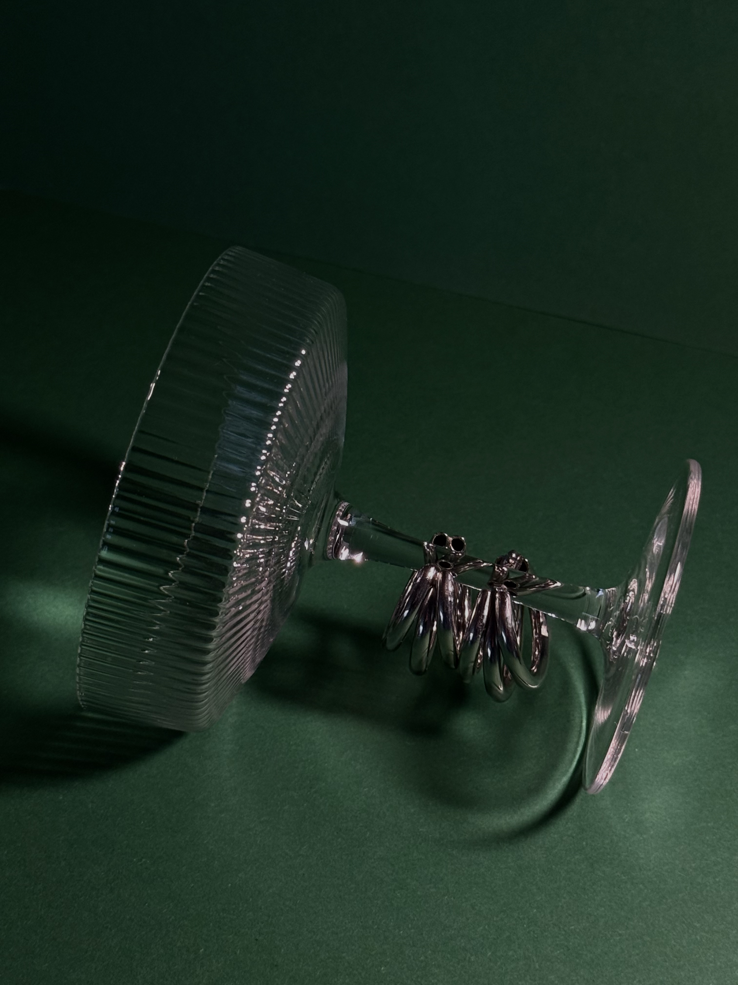 Een wijnglas ligt op zijn zijkant op een groene ondergrond, met polijsterijen die in het glas hangen.