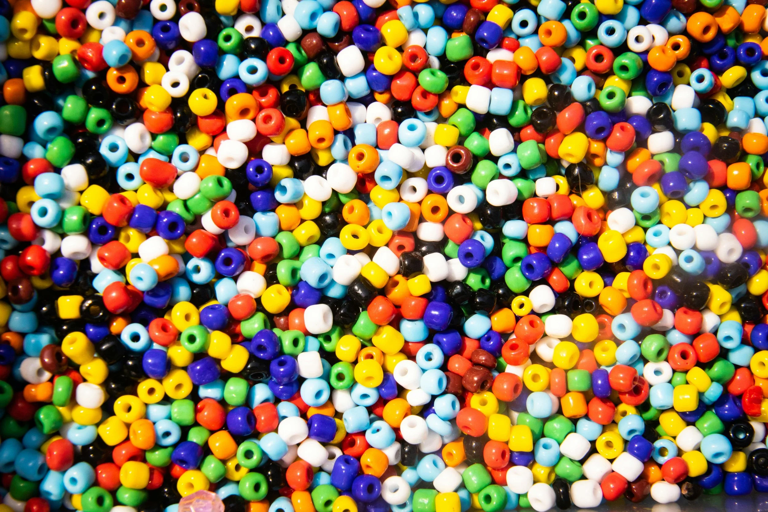 Close-up view of multicolored plastic beads in various shades including white, black, blue, green, yellow, orange, and red.
