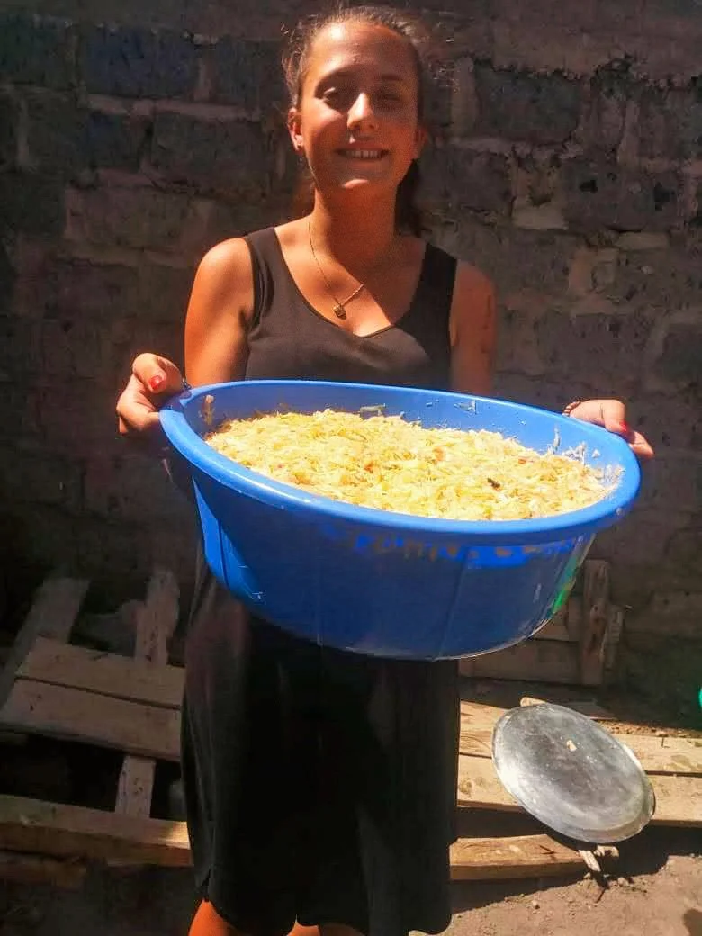 Eine junge Frau namens Nathalie Narbel lacht glücklich und hält einen grossen blauen Topf mit Pasta in die Kamera. Sie hat für die obdachlosen Strassenkinder von Nairobi-Afrika gekocht