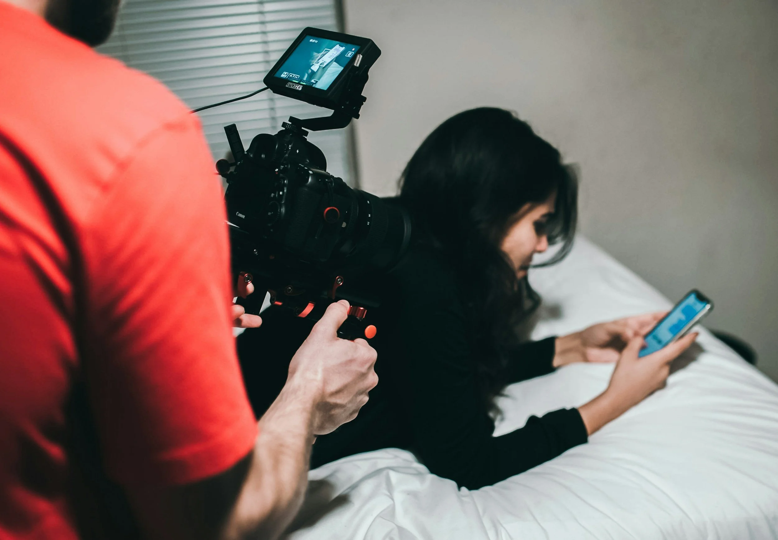 Content creator using a smartphone while being filmed during a social media campaign production shoot.