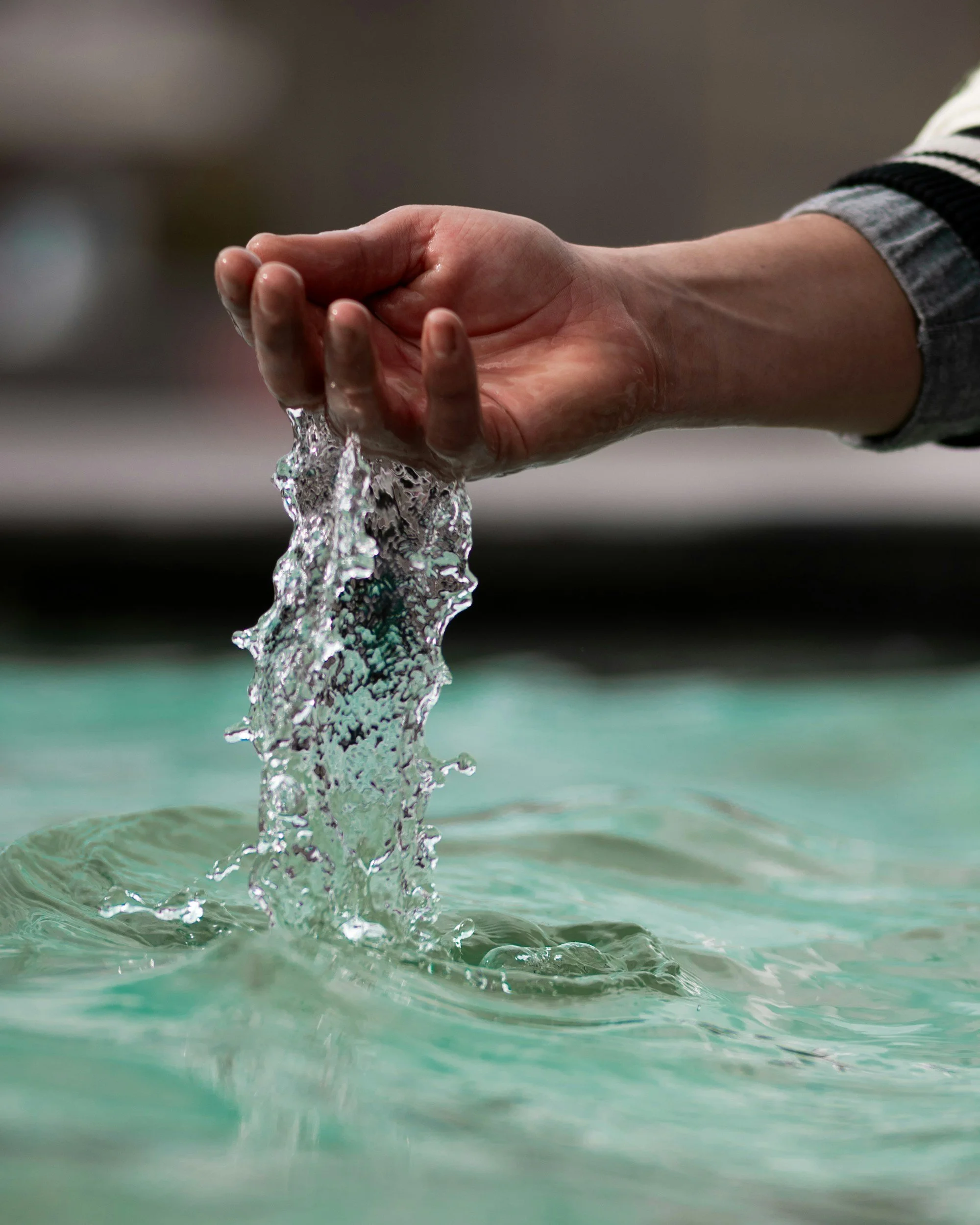 Close-up of a hand touching flowing treated water, symbolizing safer human interaction and cleaner outcomes in produced water operations.