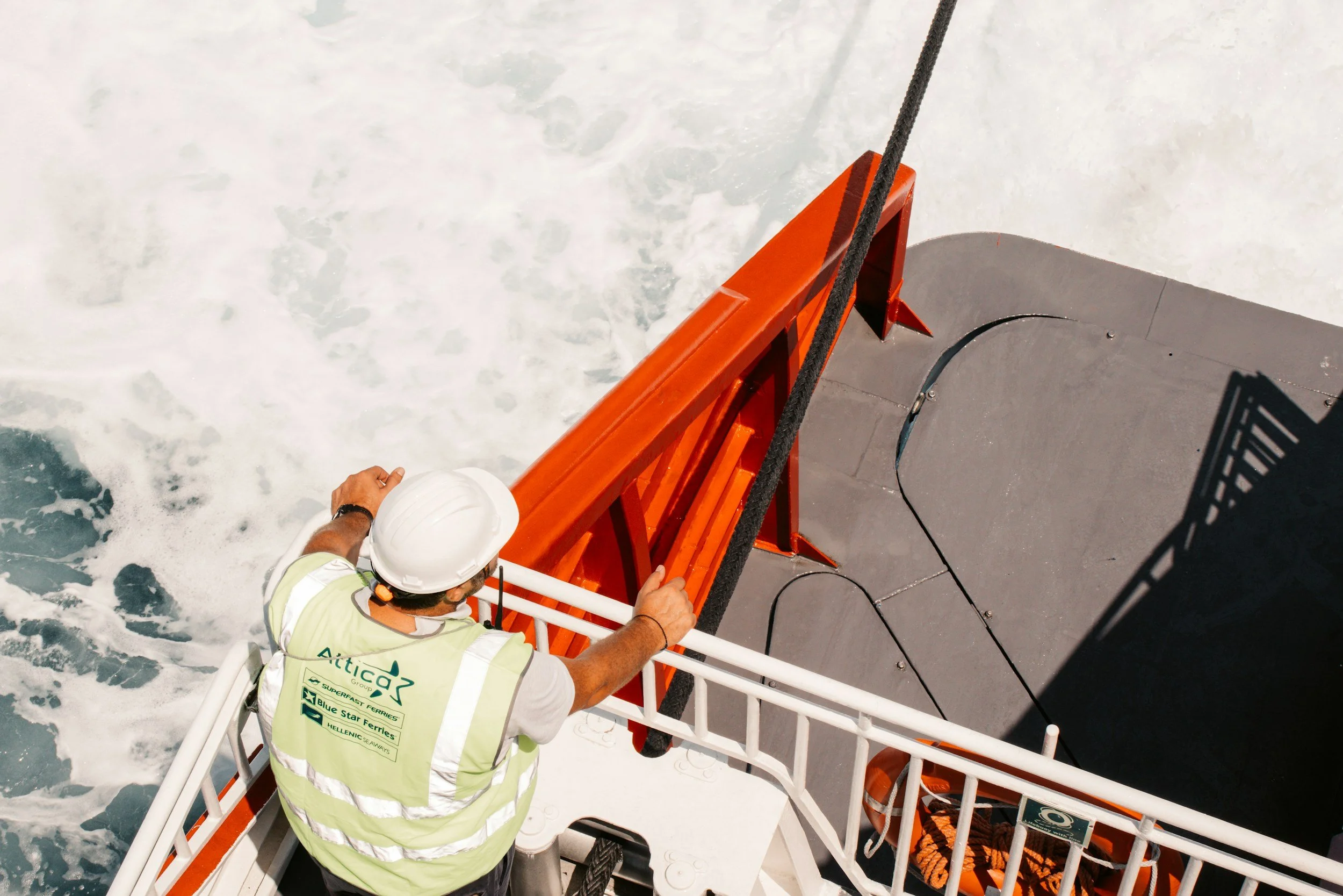 Worker in safety gear standing on an industrial platform above moving water, inspecting site conditions in a produced water operation.