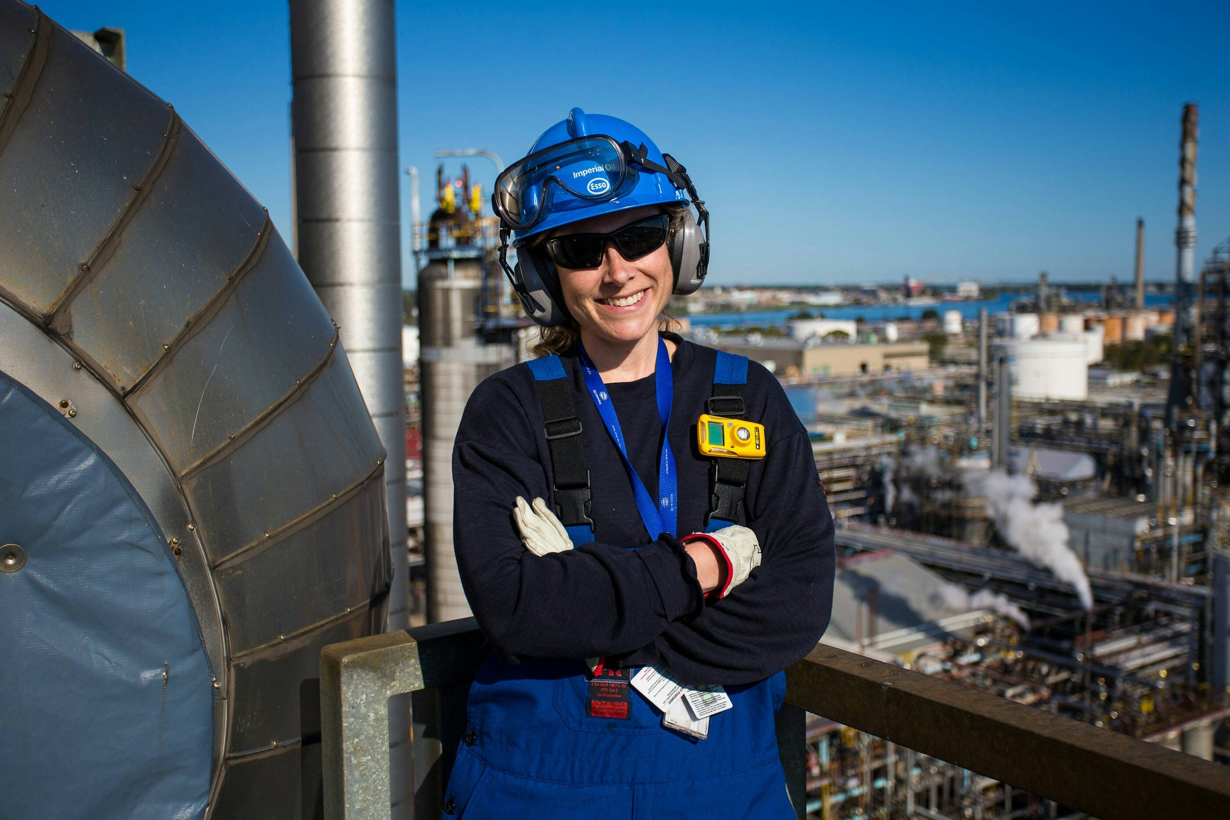Industrial operator in safety gear standing above a large facility, representing field-informed system design.