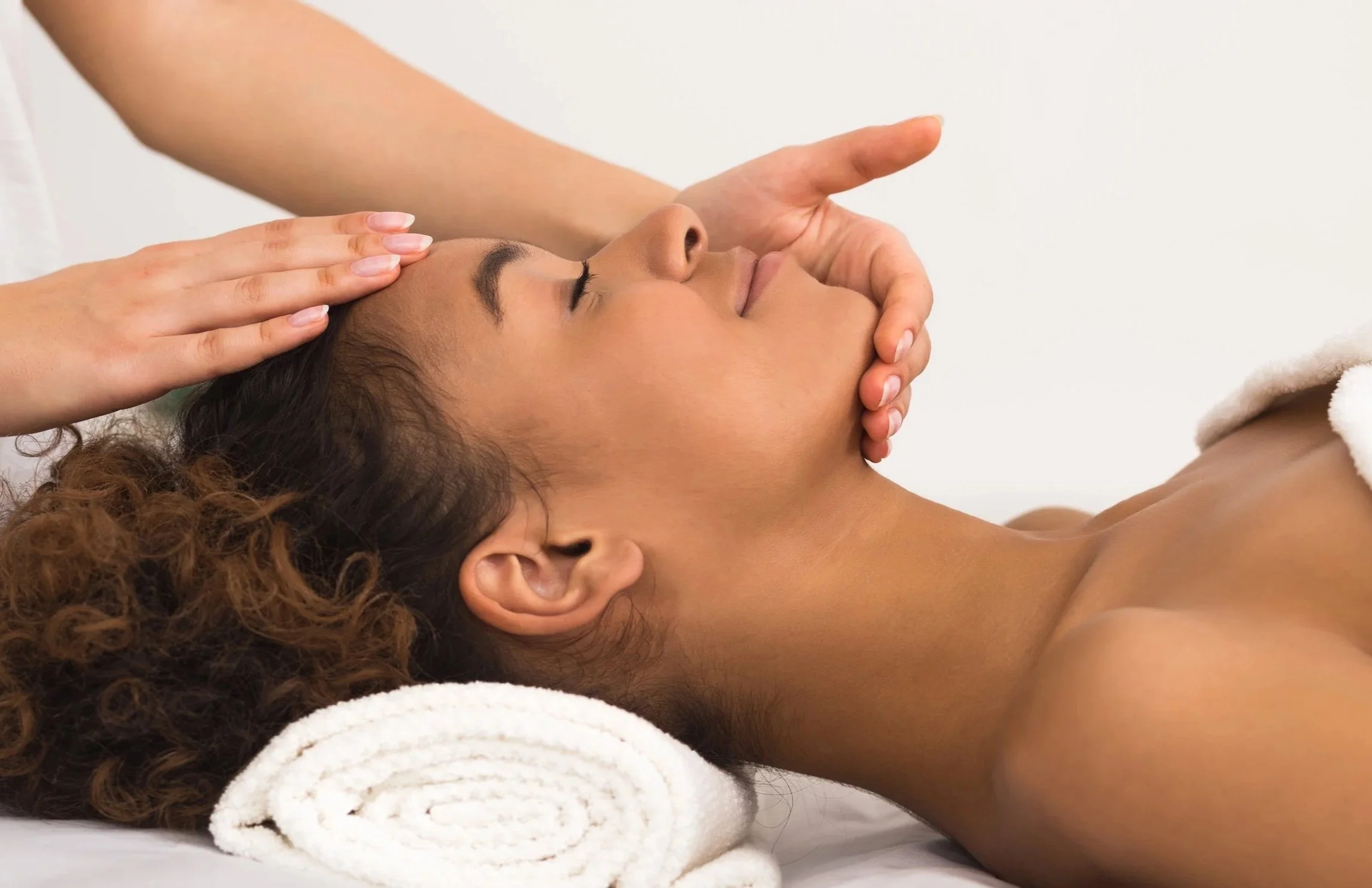 Woman receiving a relaxing facial massage from a therapist at spa