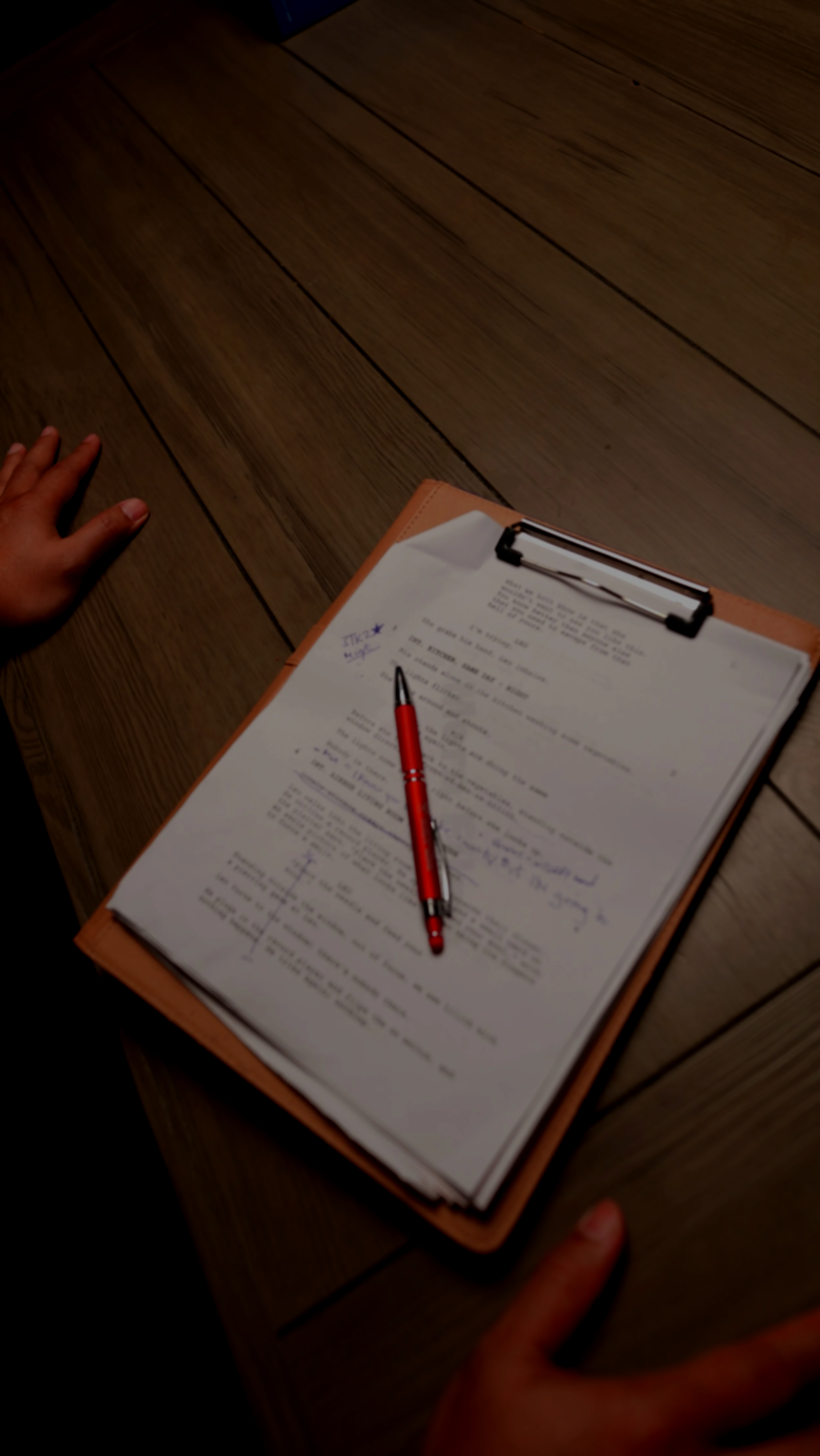 A clipboard with papers, a red pen, and handwritten notes on an office desk.