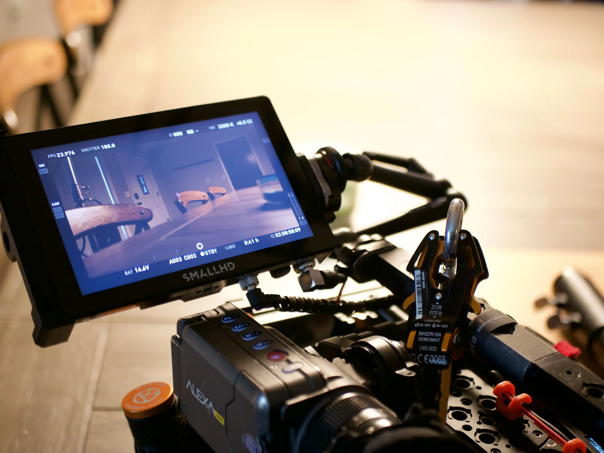 Close-up of a camera monitor on a film or video production set, showing an empty room with chairs and walls, as seen through the monitor.