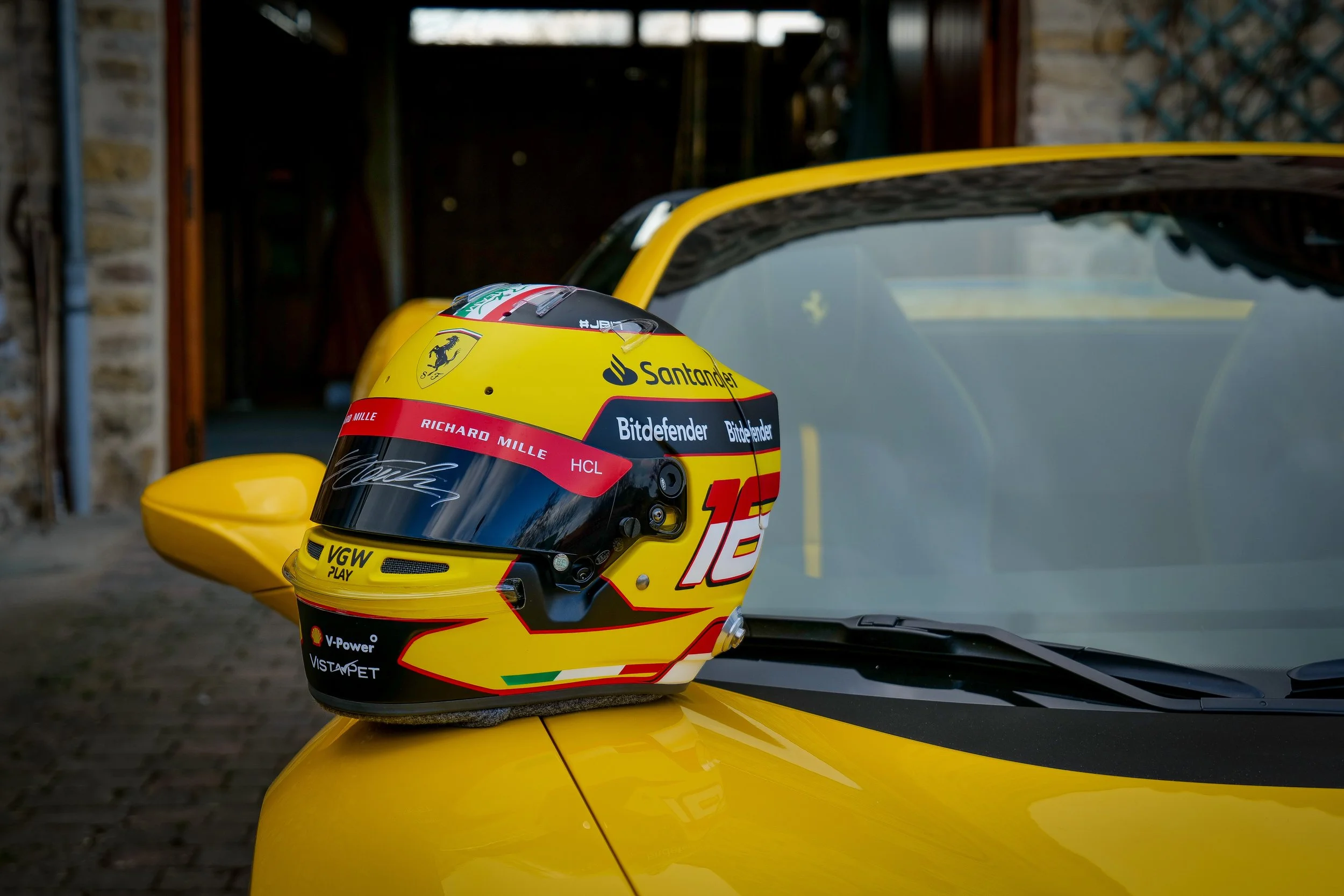 Un casque de course posé sur le capot d'une voiture jaune.
