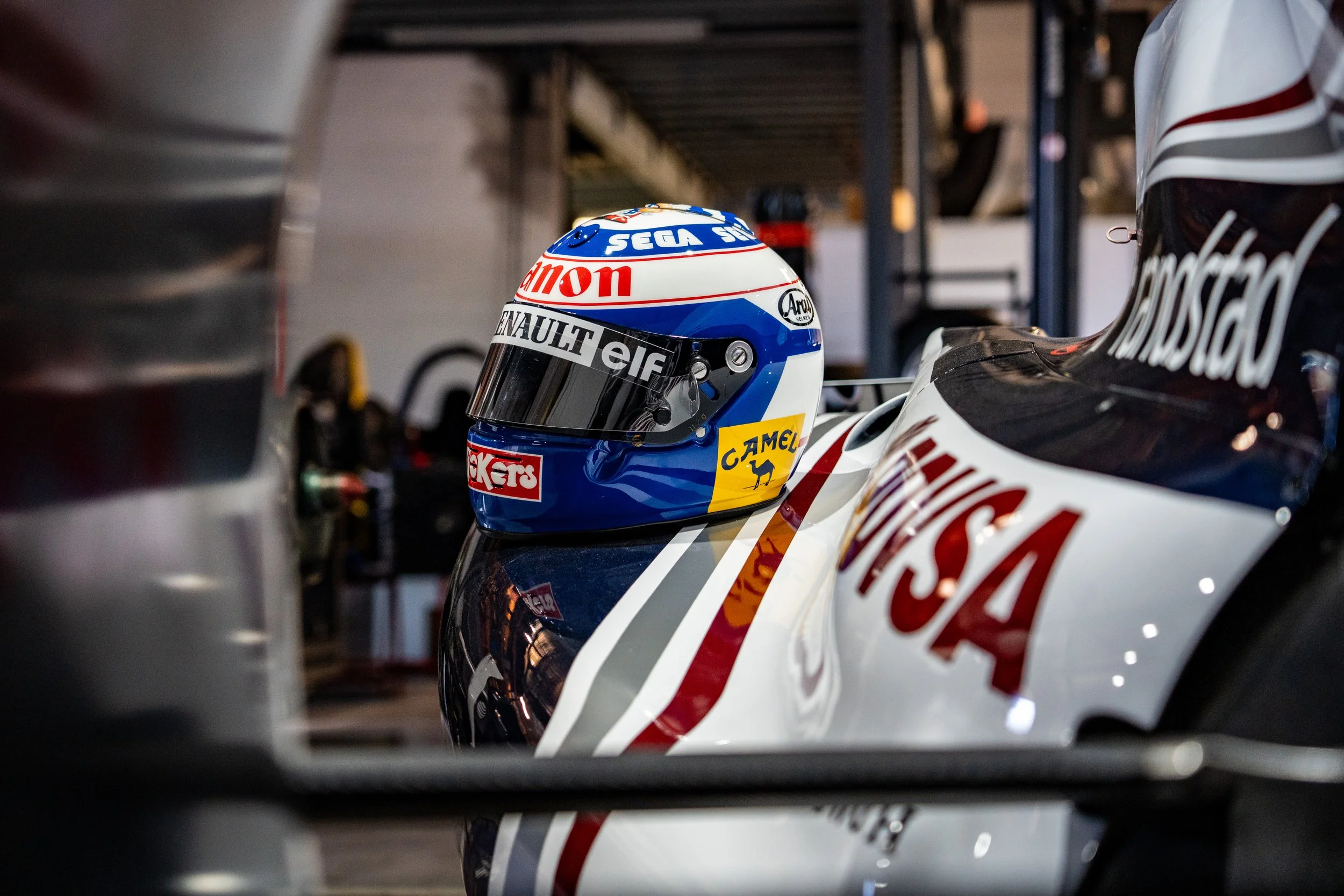 Casque de course de Formule 1 avec logos de Renault, Elf, Camel, et autres, placé sur une voiture de course de l'équipe USA.
