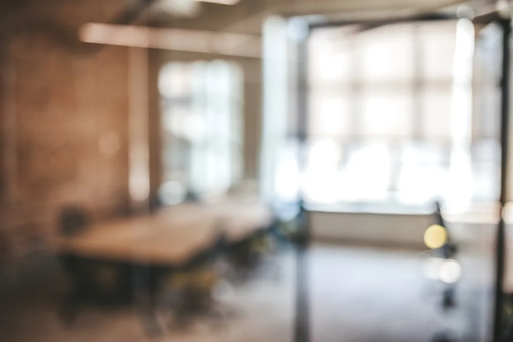 Valérie Brière - Espace de bureau avec grandes fenêtres, meubles et lumière naturelle.
