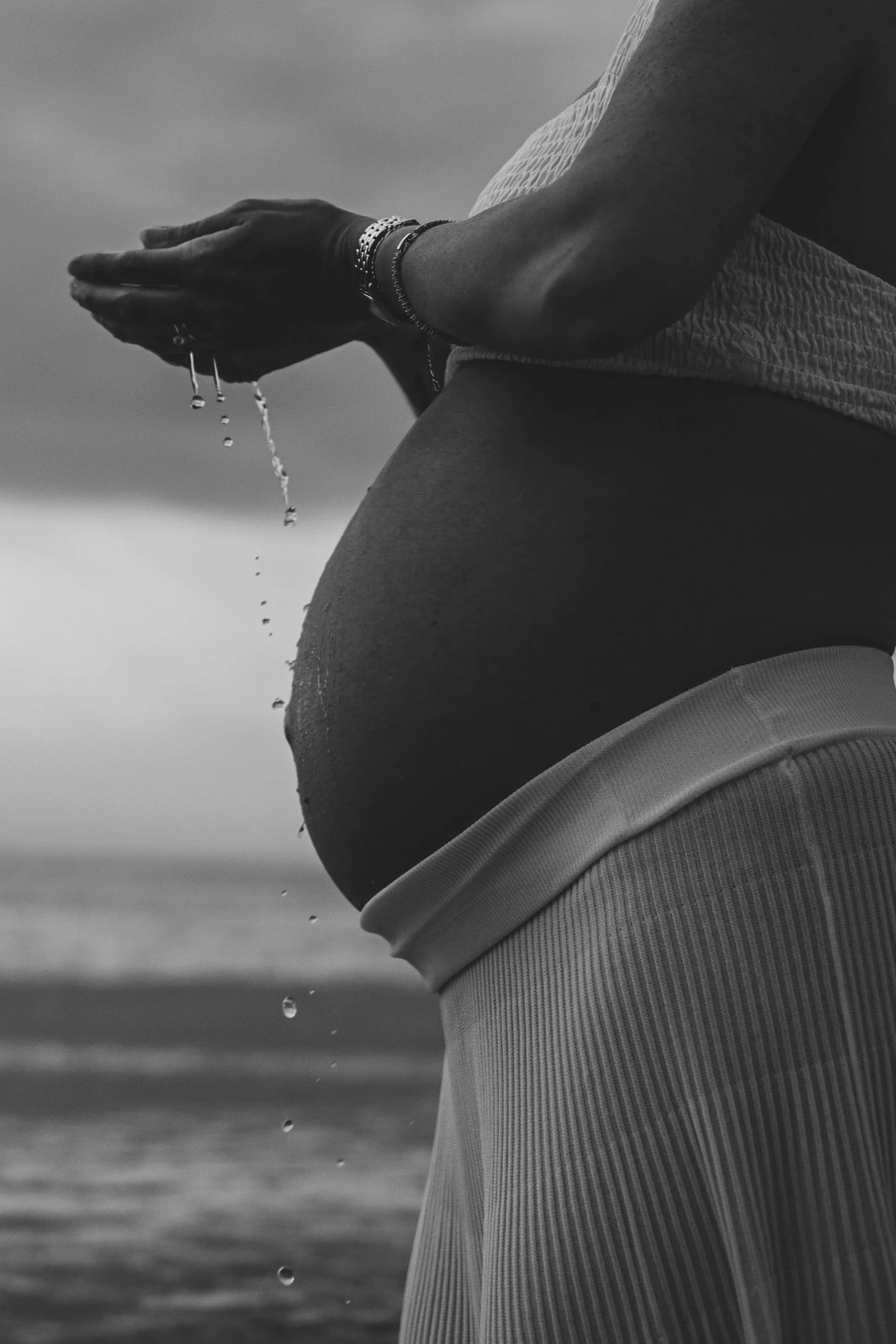Bambino con capelli castani e occhi azzurri, che sorride mentre viene aiutato a mangiare con un cucchiaio da una persona con unghie rosse e un anello.