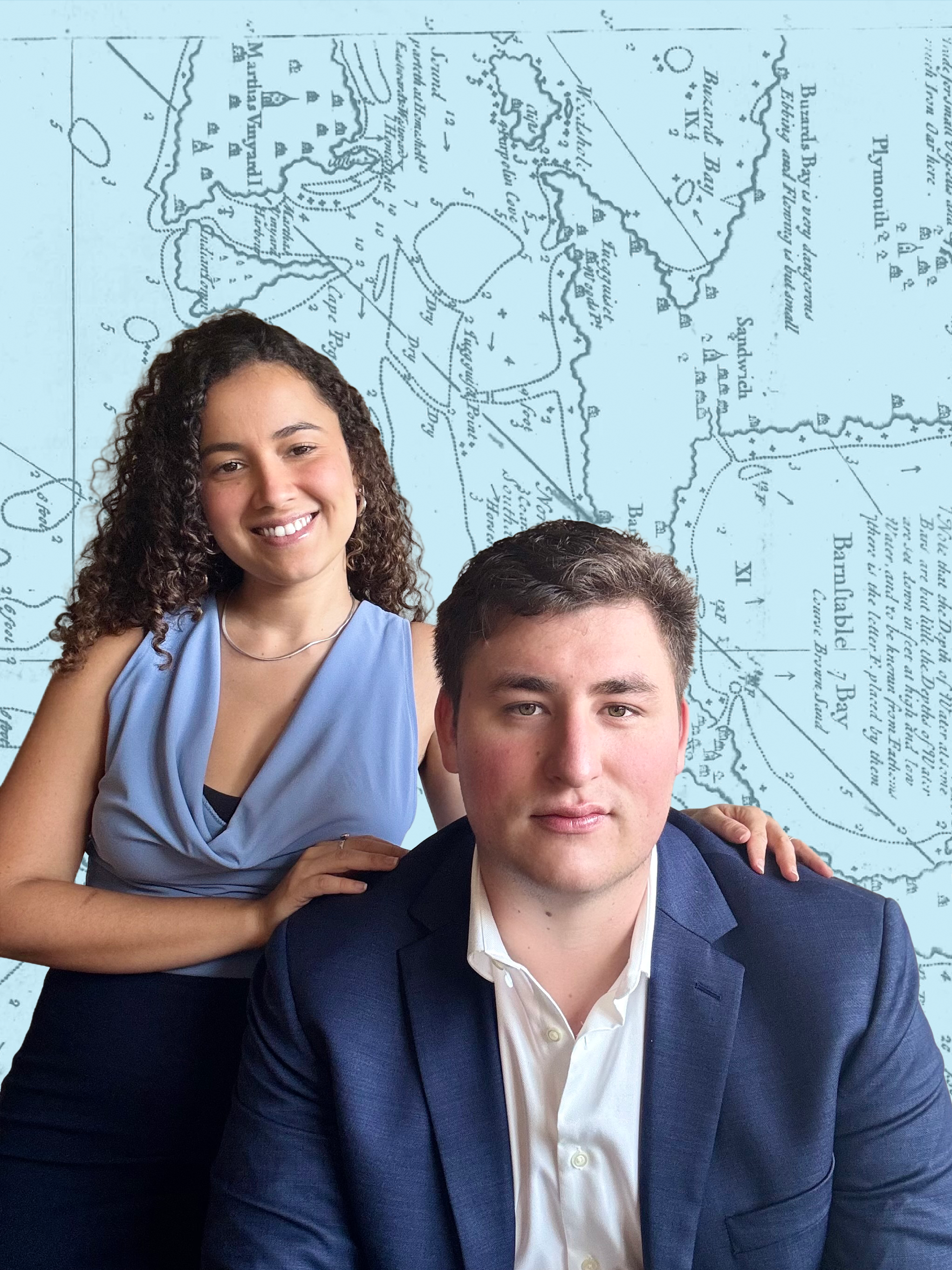A man and a woman pose in front of a background featuring a vintage map. The woman has curly hair, wears a light blue sleeveless top, and is smiling. The man has short dark hair, wears a dark blue blazer over a white shirt, and has a neutral expression.