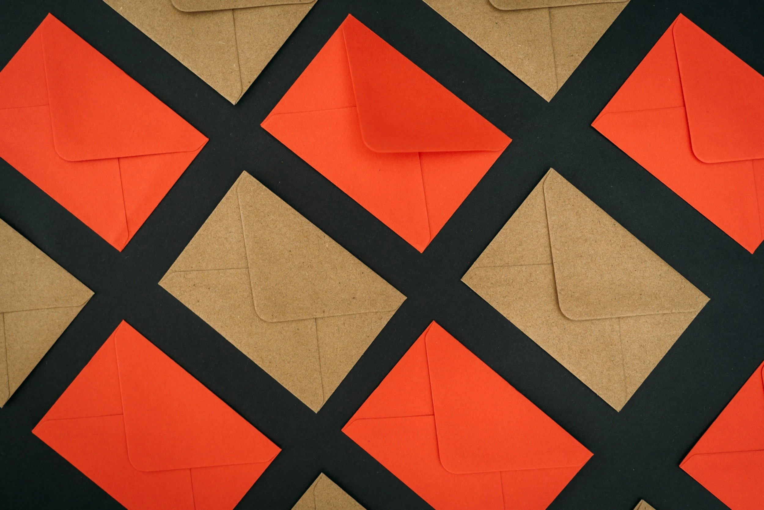 Multiple orange and brown envelopes arranged in a diagonal pattern on a black and brown background.