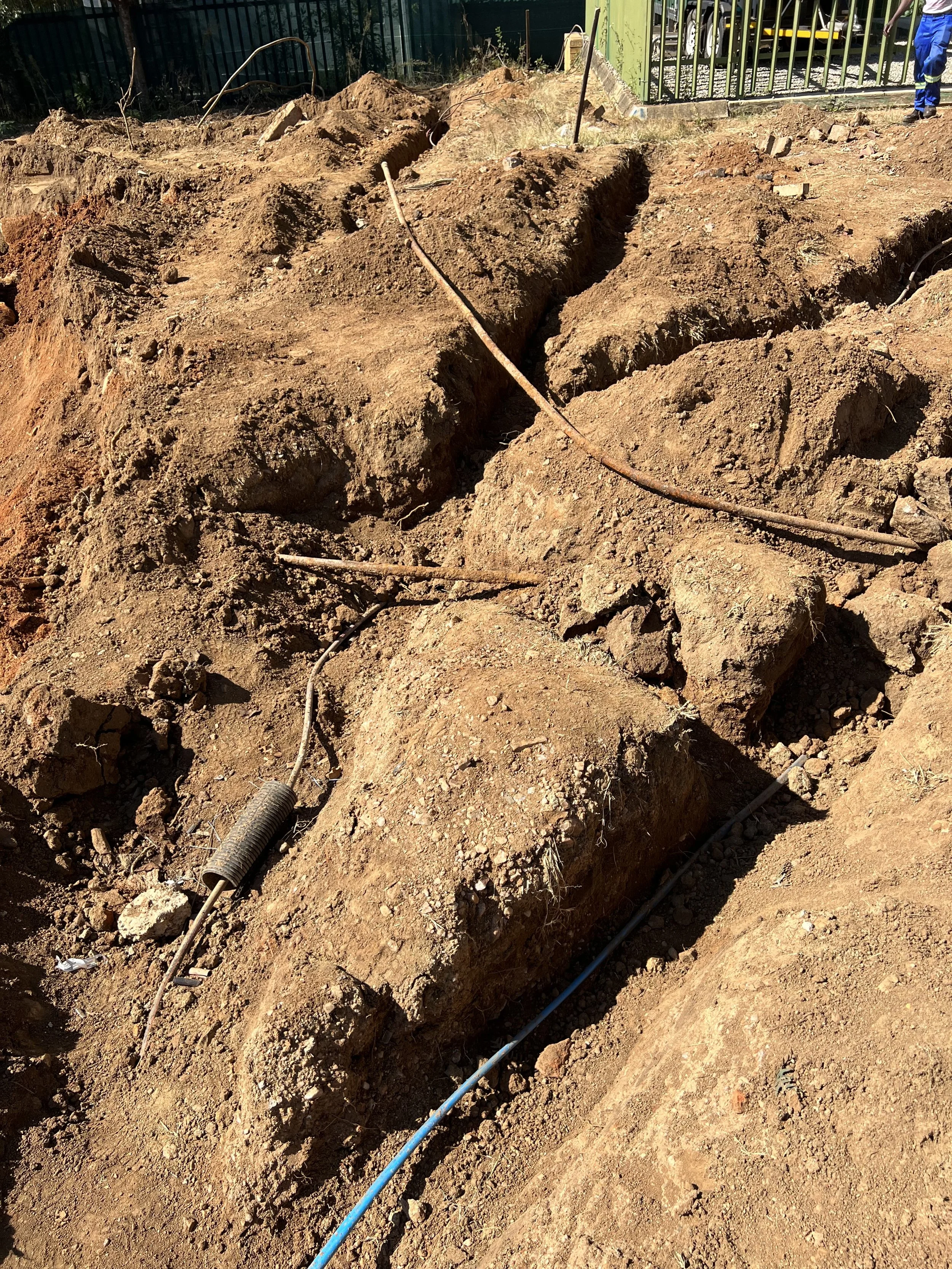 Construction site showing trenches in dirt with electrical wires laid in the trenches. all Utilities Exposed in a safe manner