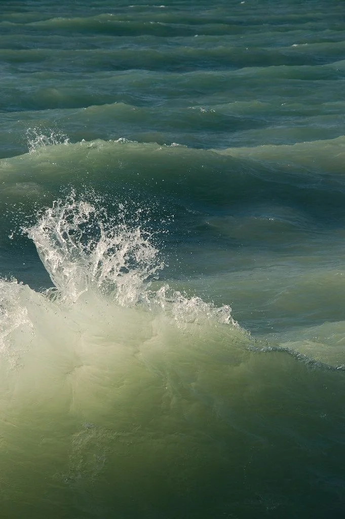 Waves crashing in the ocean with greenish-blue water.