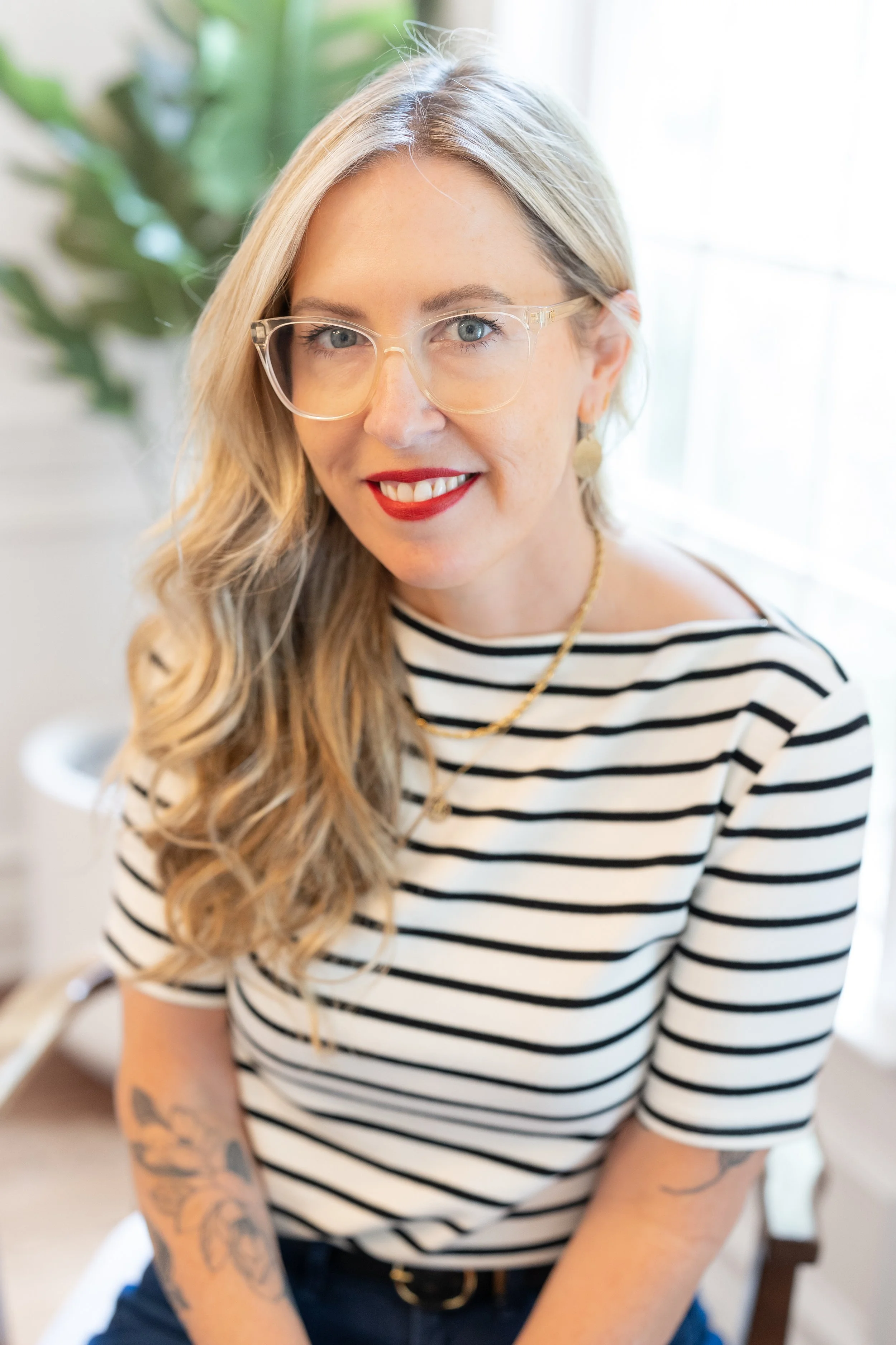 Realtor Annie Blue Pettry's Headshot. She is smiling and sitting relaxed at a beautiful dining room table.