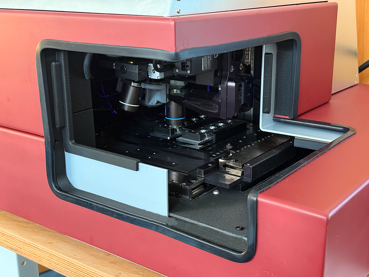 GramRay the most advanced Raman microscope with its stage and objective lenses visible inside an open red case.
